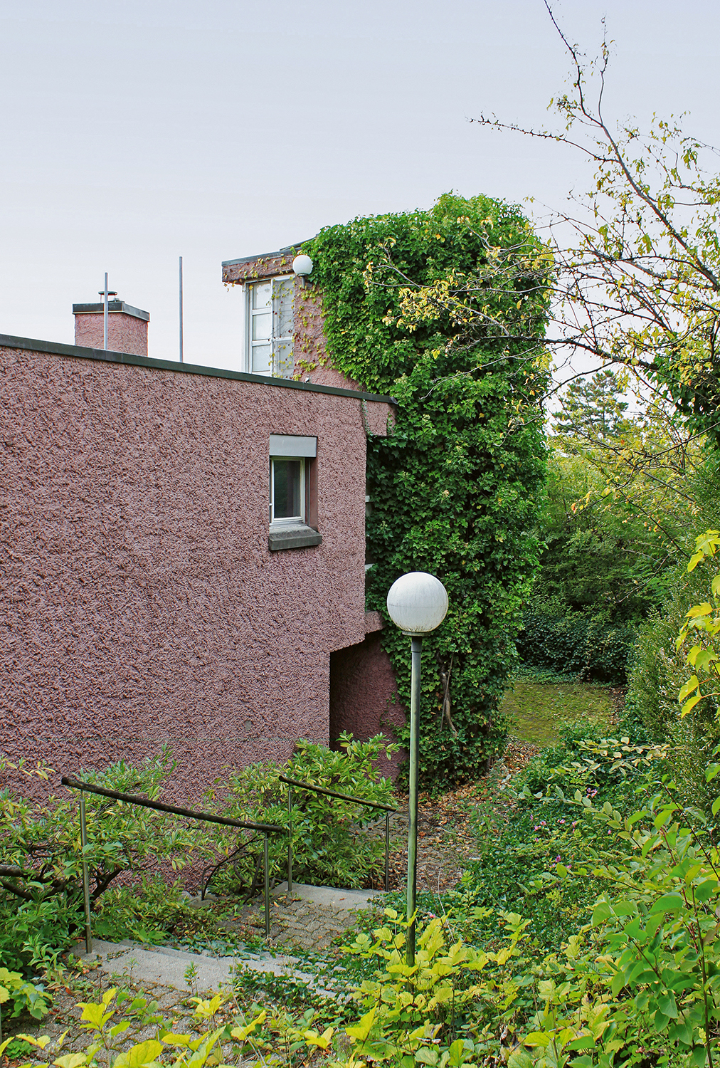 Über eine Treppe gelangt man zum Eingang des Gebäudes. Im efeuüberwucherten Bauteil befindet sich das Treppenhaus.
