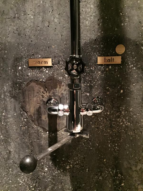 Sul beton tinto di nero delle docce del bagno turco si intravedono sottili crepe e tracce di riparazioni.