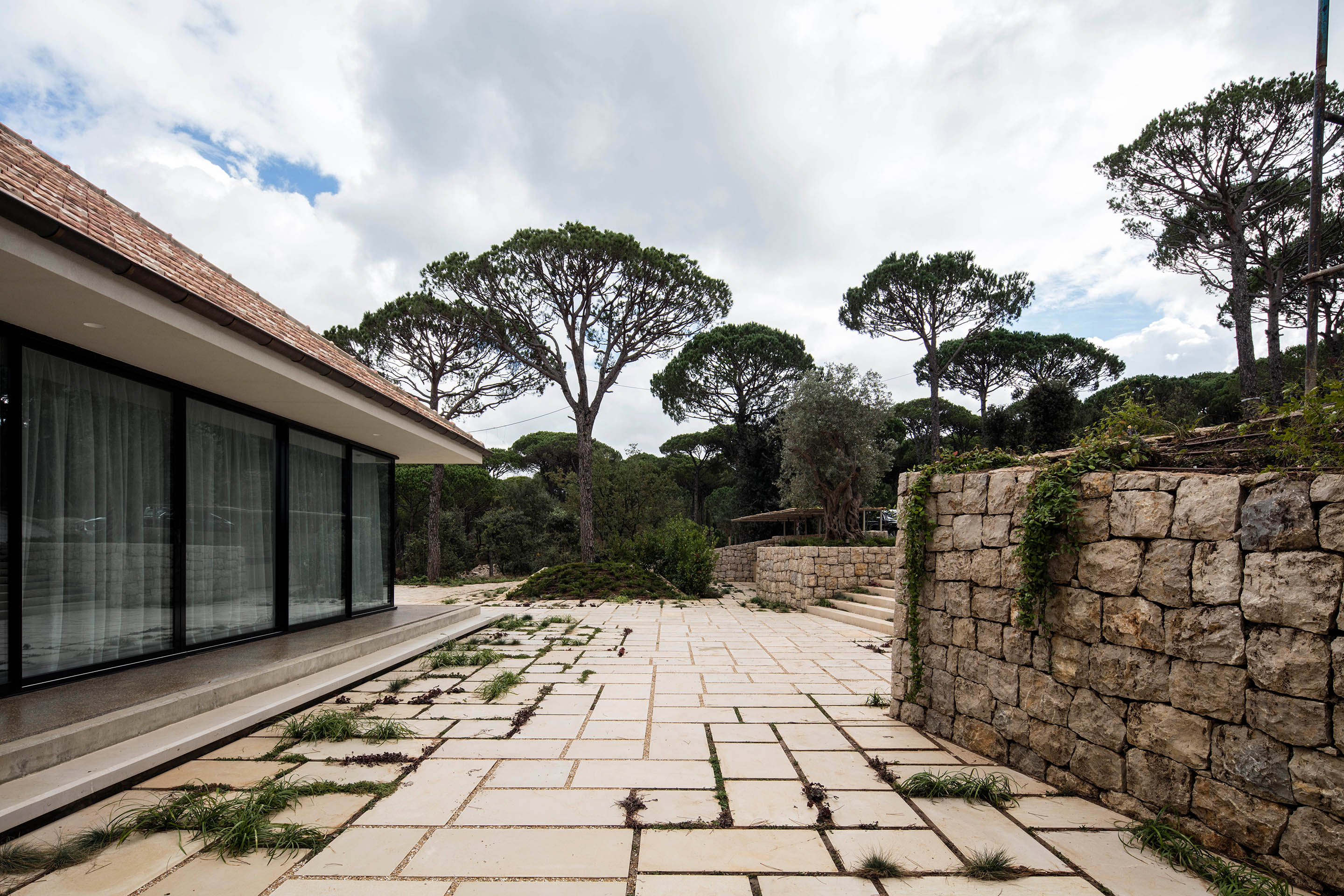 Das Haus befindet sich auf einer leicht erhöhten Plattform. Das frei tragende Dach verläuft entlang der Glasfassade und erweitert den Innenraum zur Landschaft.