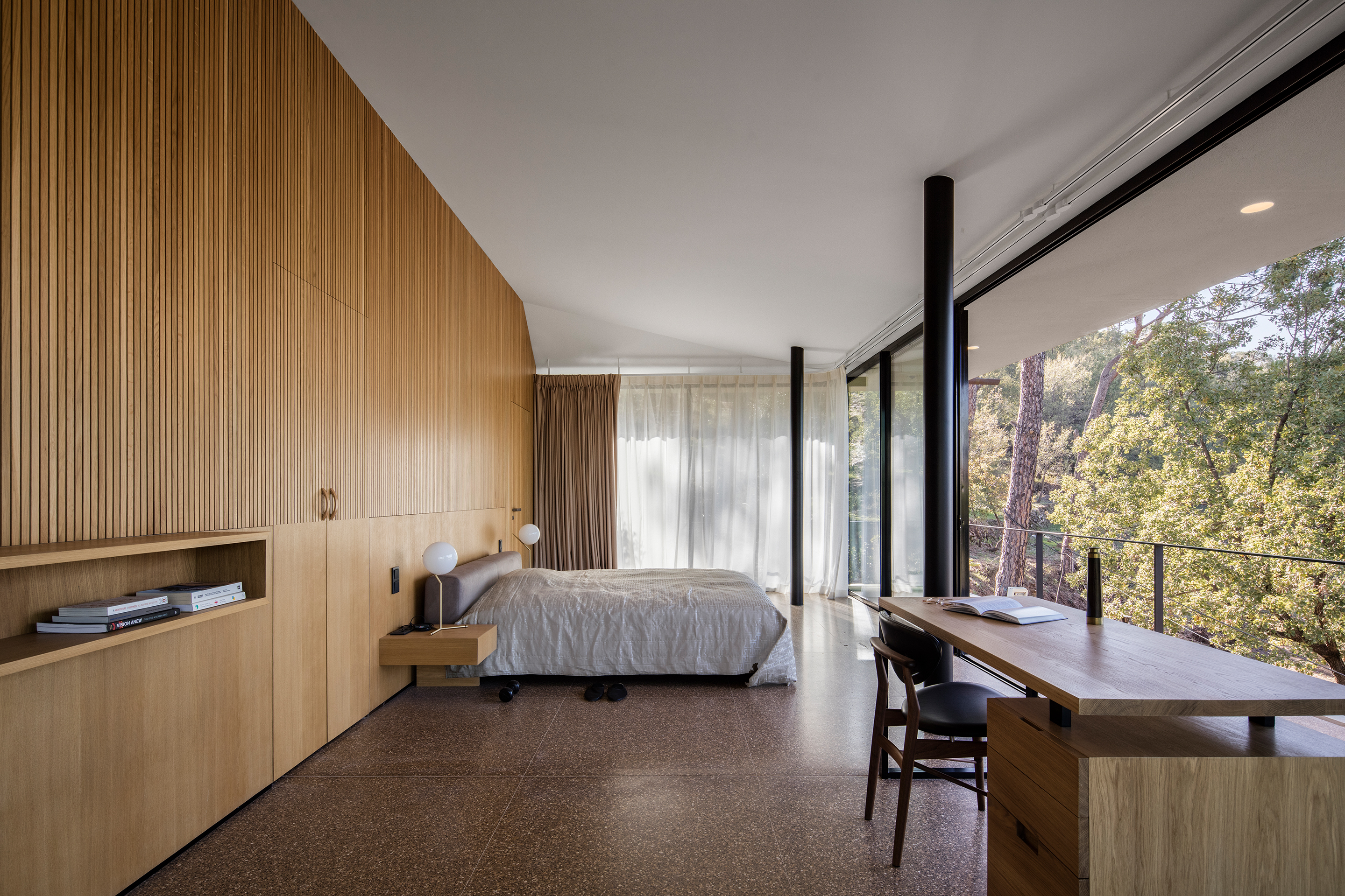 Die untere Decke im Schlafzimmer spiegelt einen intimeren Raum wider. Innentüren und Schränke sind nahtlos in die vertikalen Eichenpaneele der Innenwände integriert.