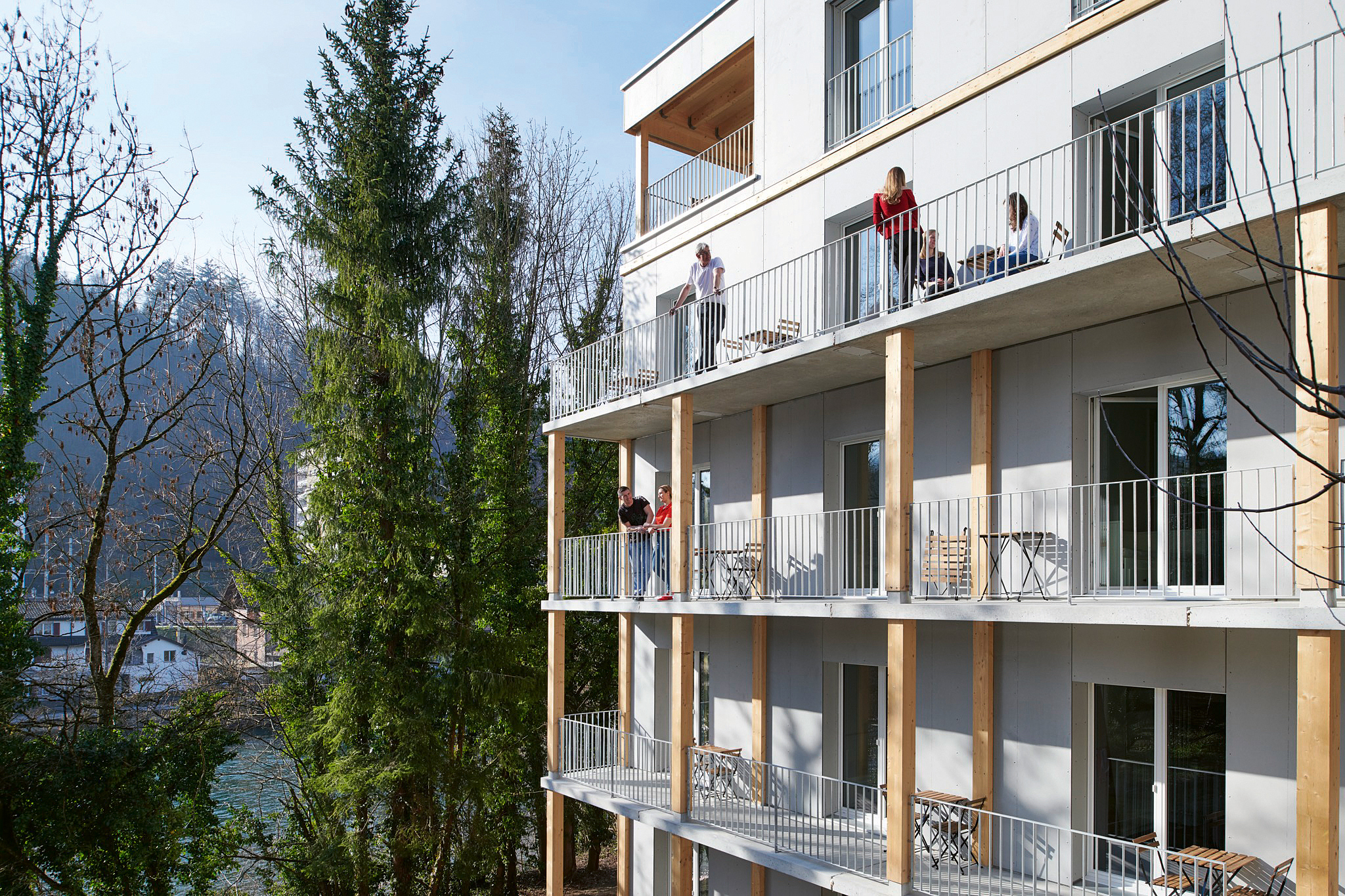 Südseitig sind vor der Holzkonstruktion aus brandschutz­technischen Gründen betonierte Fluchtwege angebaut, die aber auch als Balkone beliebt sind.