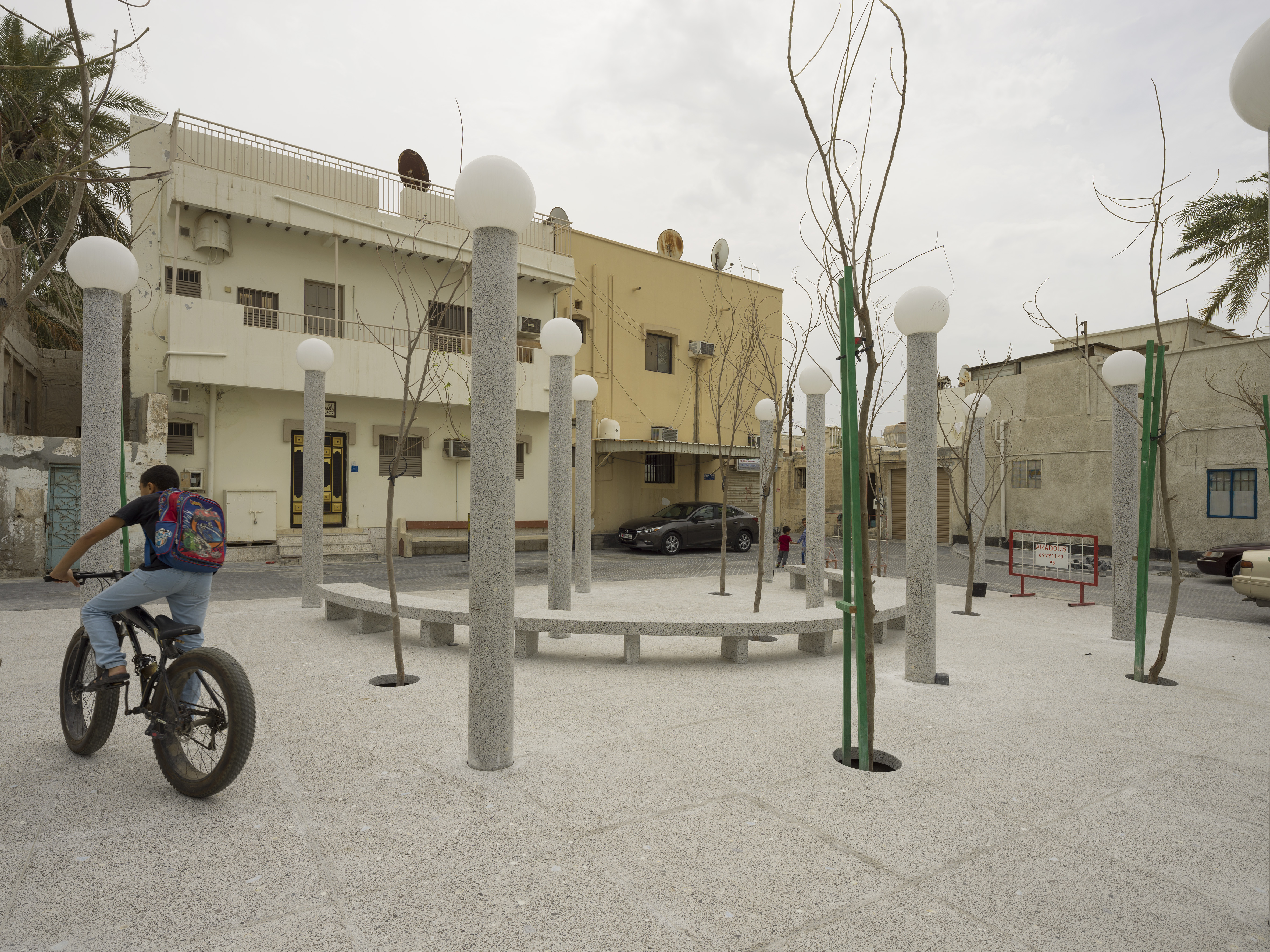 Child riding a bicycle across one of the 18 public spaces designed as microclimates within the city.