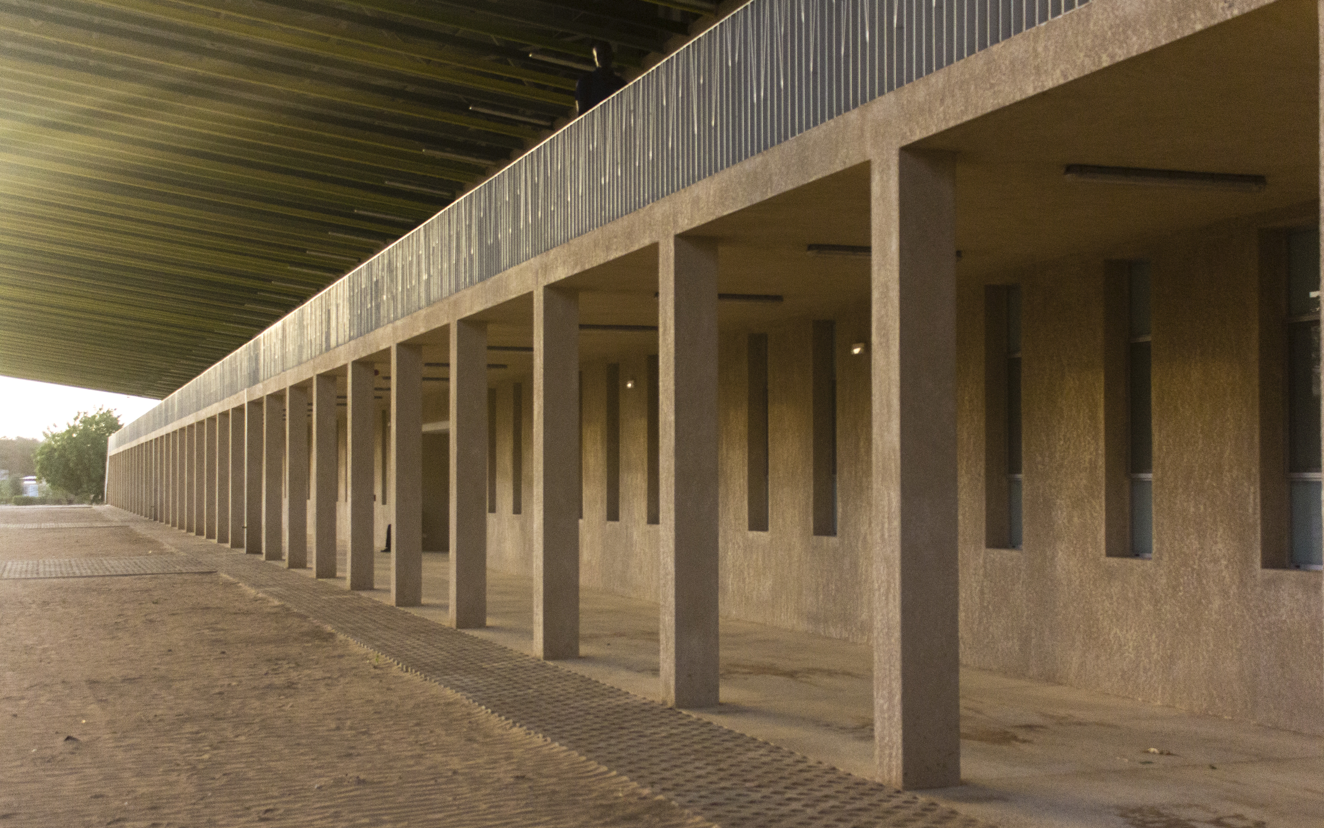 The ramp and stairs lead to an exterior corridor, supported by a row of square pillars, connecting the upper level’s different spaces. The ramp and stairs lead to an exterior corridor, supported by a row of square pillars, connecting the upper level’s different spaces.