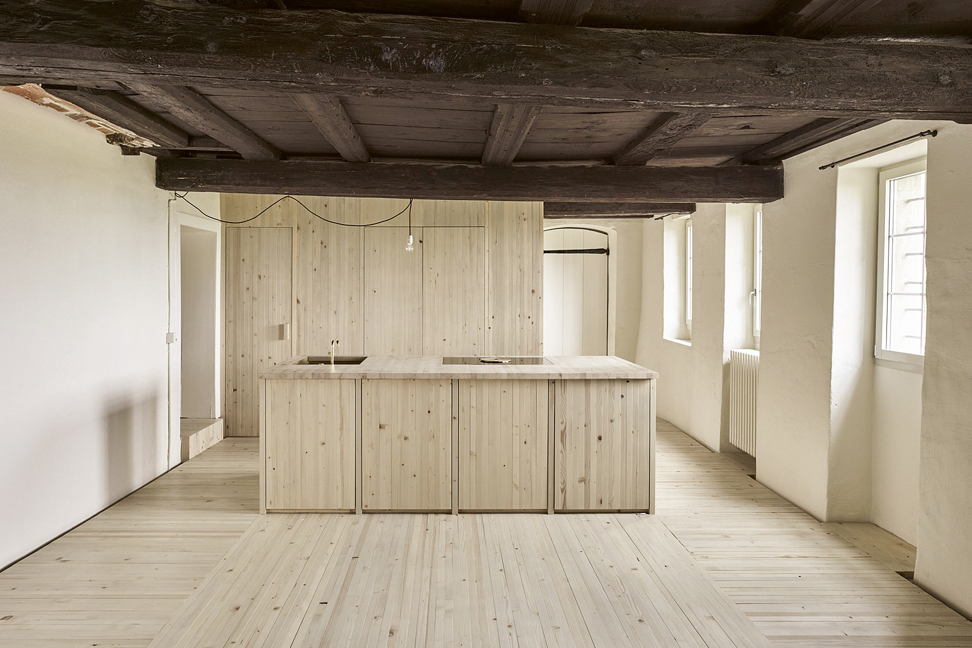 In der Küche im EG dominieren tatamiartig verwendete Holzmodule den Bestand. Die russgeschwärzte Decke wirkt isoliert.