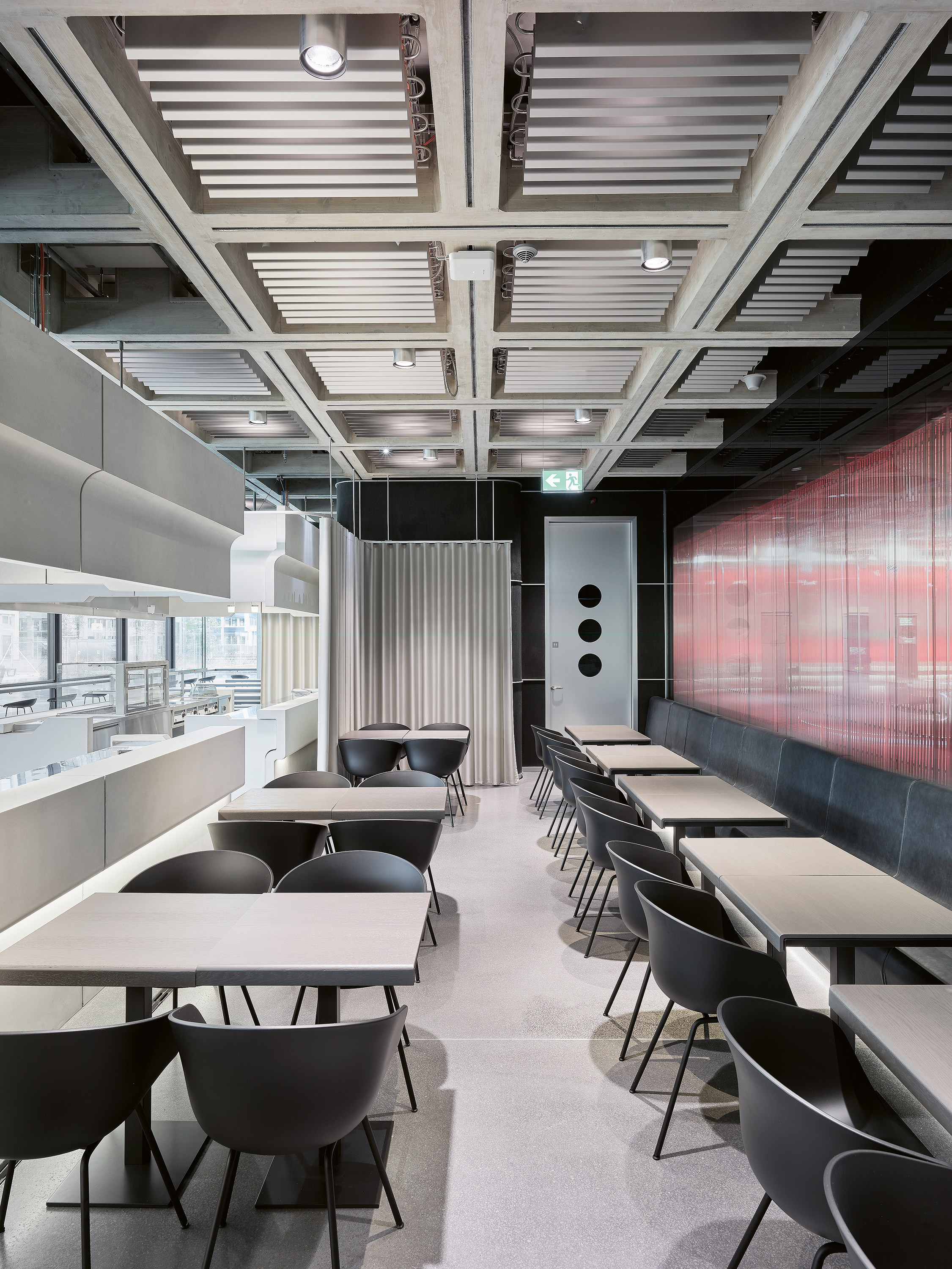 Durch die Glaswand im hinteren Bereich des Restaurants (hier rot angeleuchtet) blickt man direkt in ein Studio.