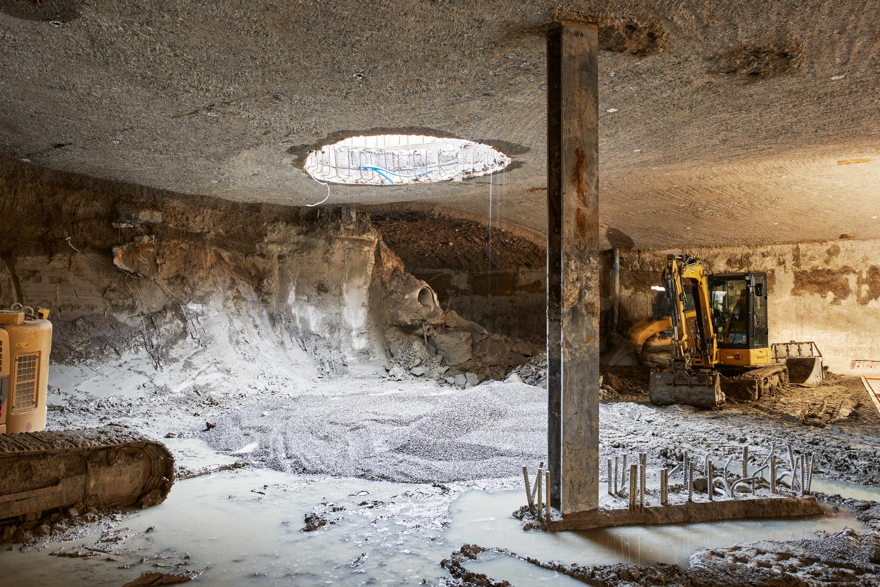 Die Tiefgarage wurde in Deckelbauweise erstellt: Nachdem die Decken, Wände und Stützen von oben her betoniert worden waren, hub man mit Baggern das Erdreich aus dem Volumen aus. Anschliessend folgte das nächste Untergeschoss. Im Bild: 1. UG.