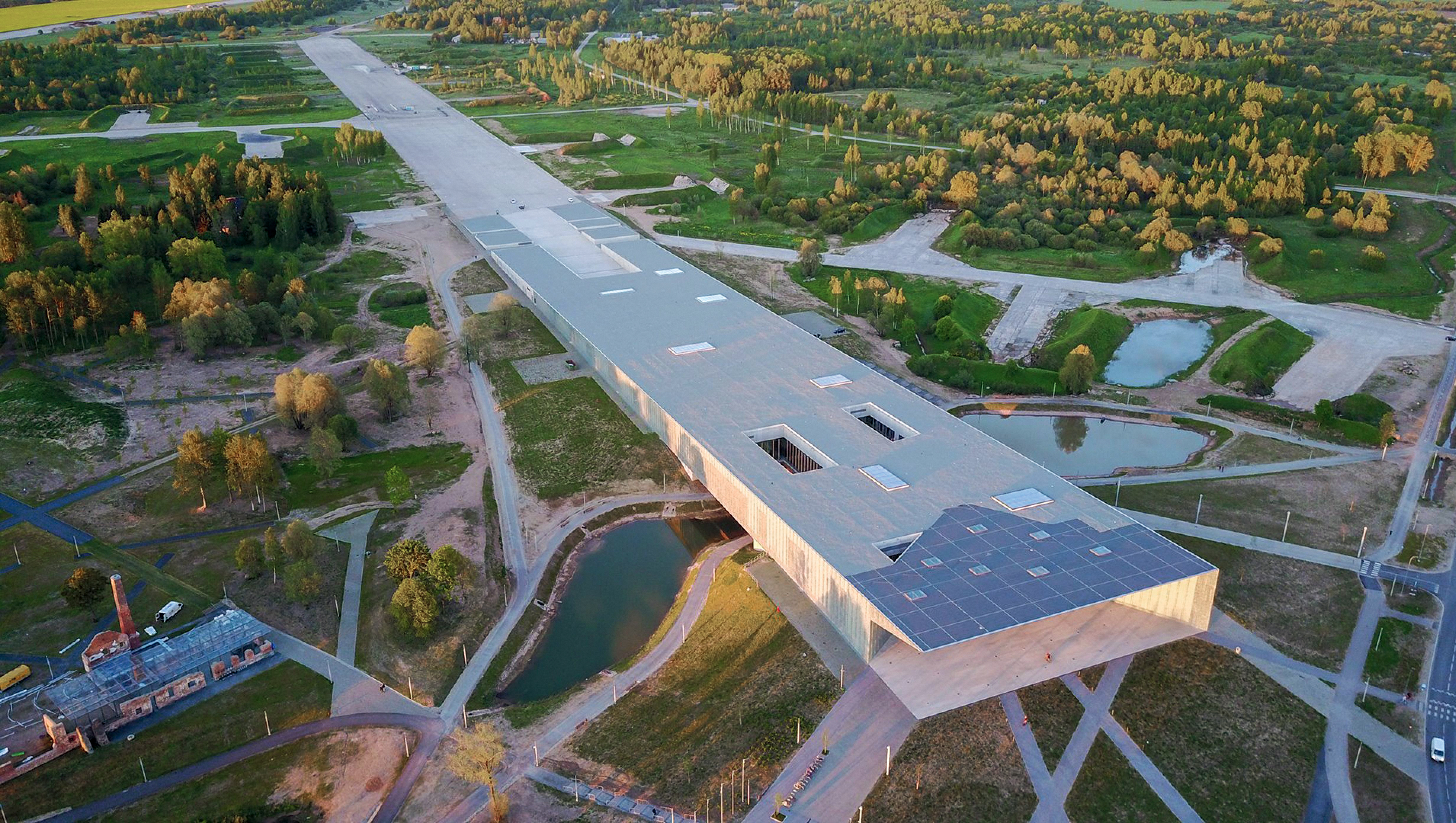 Musée national estonien, Tartu. La piste d’aéroport d’une ancienne base militaire soviétique a servi de fondement au plan, allant jusqu’à donner sa forme au complexe muséal. Le bâtiment incarne à la fois le passé de l’occupation allemande et l’imposition d’un régime forcé par l’ex-URSS, et l’indépendance du pays en 1991, contribuant ainsi à la reconstruction de l’identité nationale.