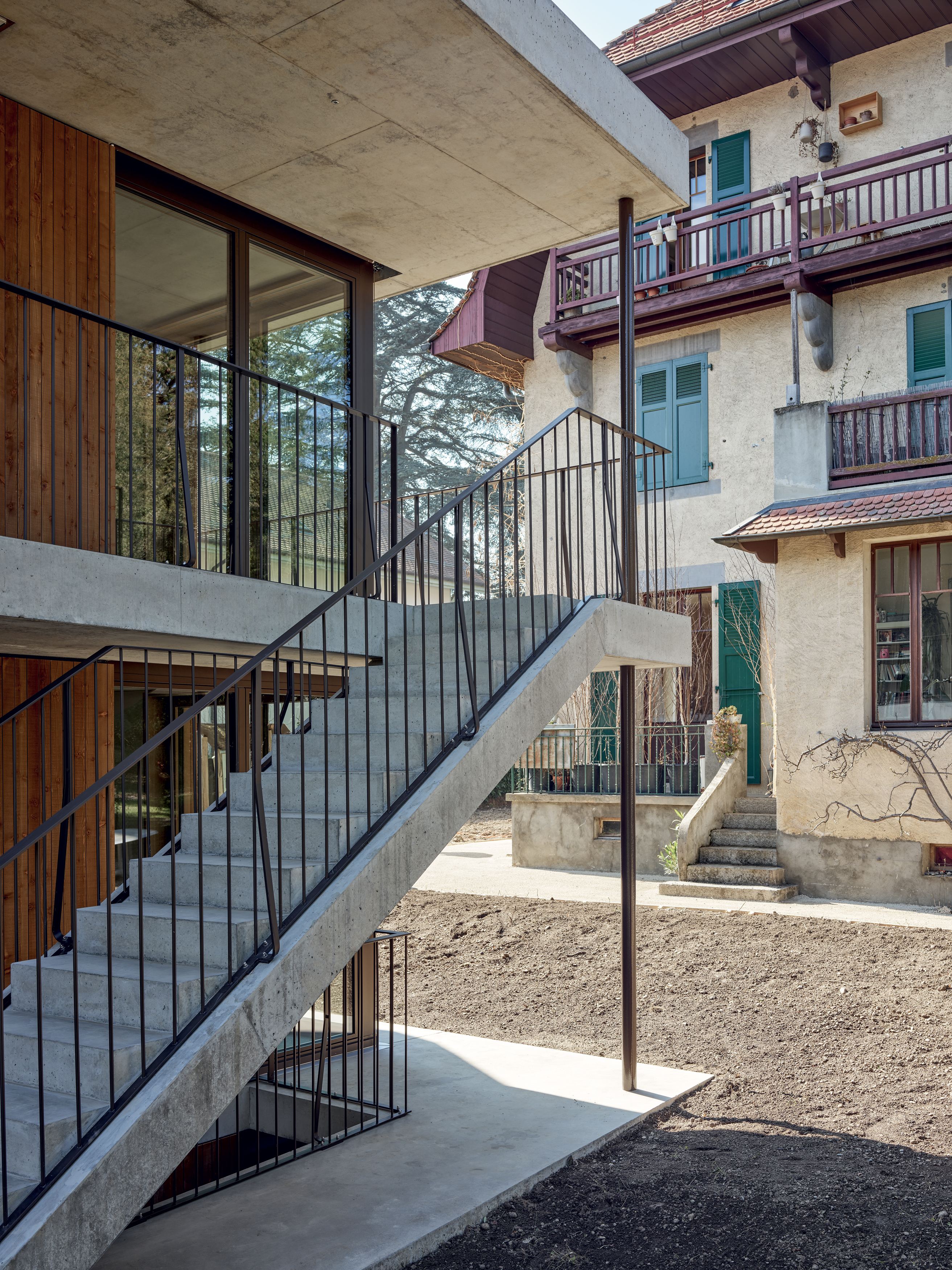 À rythme régulier devant les barreaux en métal (là où le garde-corps est boulonné au béton), une verticale supplémentaire, galbée dans un fer plat, offre un motif traditionnel, tel un balustre.