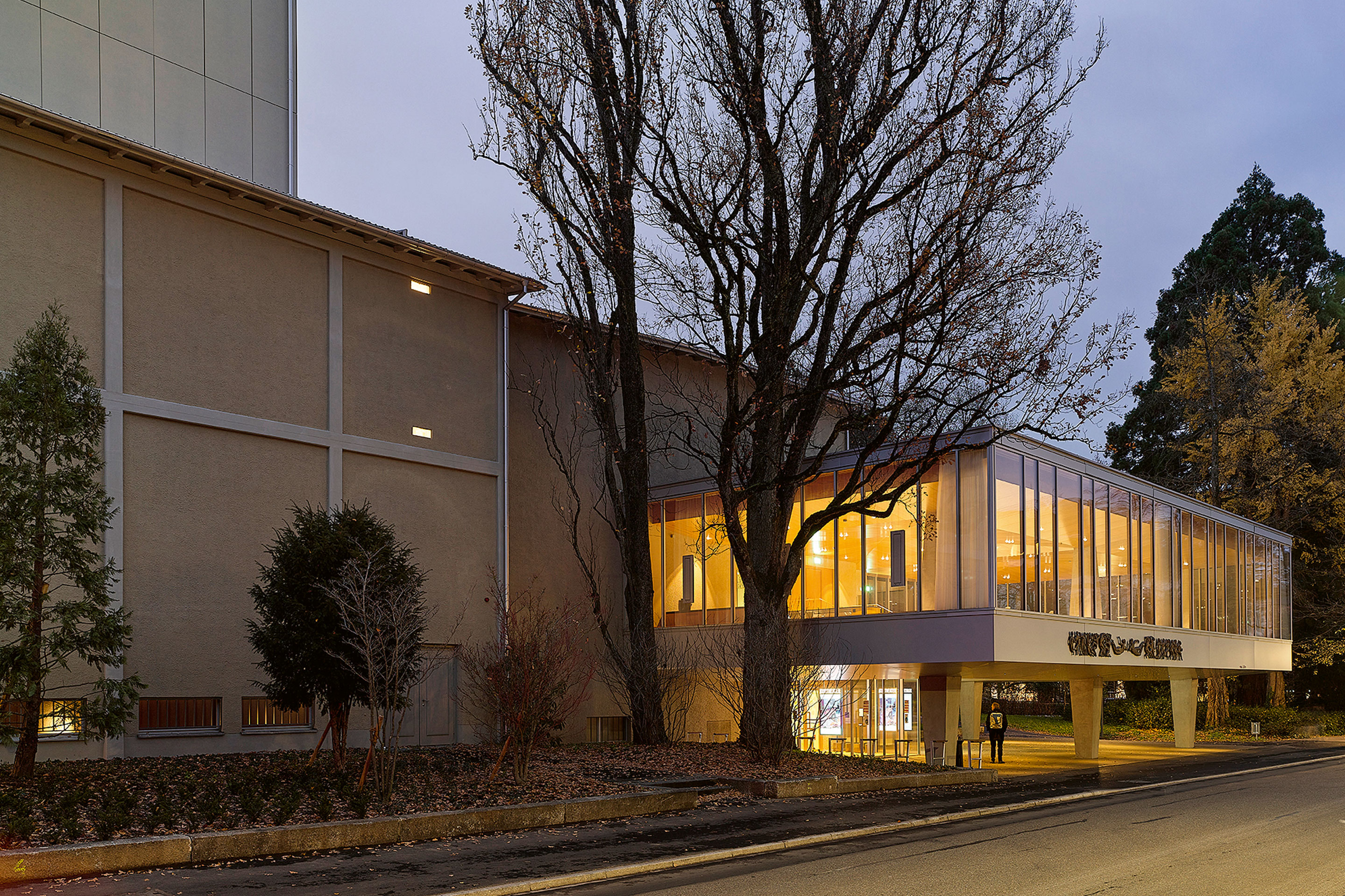 Il Kurtheater Baden, ristrutturato e ampliato con il nuovo foyer rivisitato da Boesch Architekten (illuminato sul davanti); di fianco, l'edificio che ospita il palcoscenico. Nonostante l'altezza ridotta, il soffitto dell'ingresso del foyer non viene più percepito come basso grazie alla sua forma a tenda.