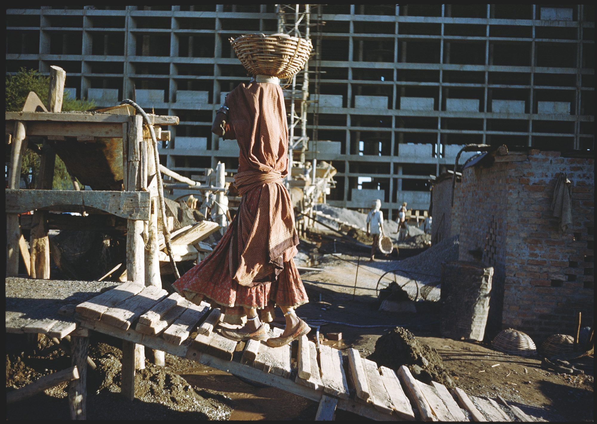 Woman carrying cement at the Capitol Complex, Chandigarh, India, in front of the Secretariat (1951–58) designed by Le Corbusier (Charles-Édouard Jeanneret, 1887–1965). 1956.