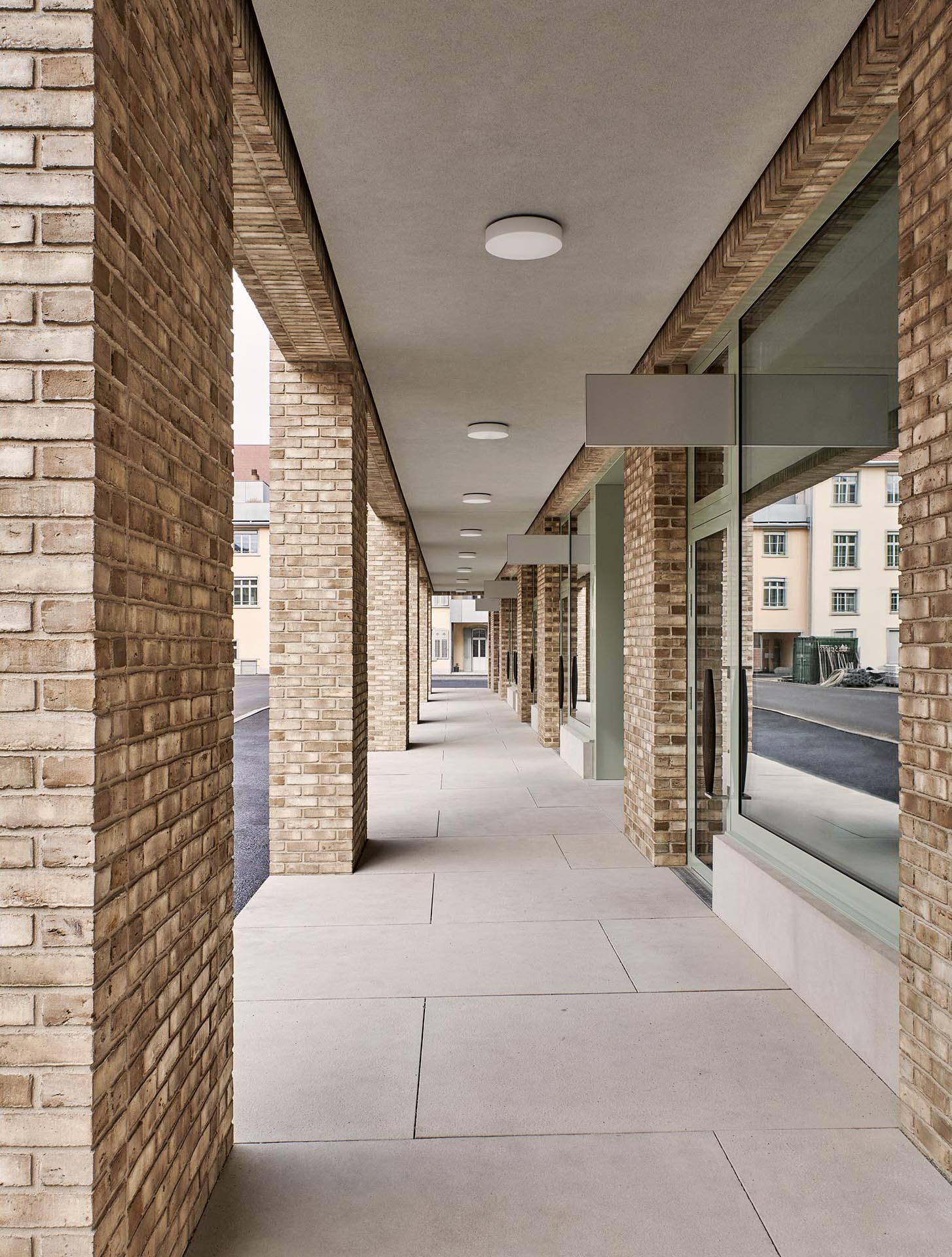 Arkaden im Erdgeschoss des zur Quartierstrasse vierzeiligen Baus bilden Zugänge zu kleinen Gewerbeeinheiten.