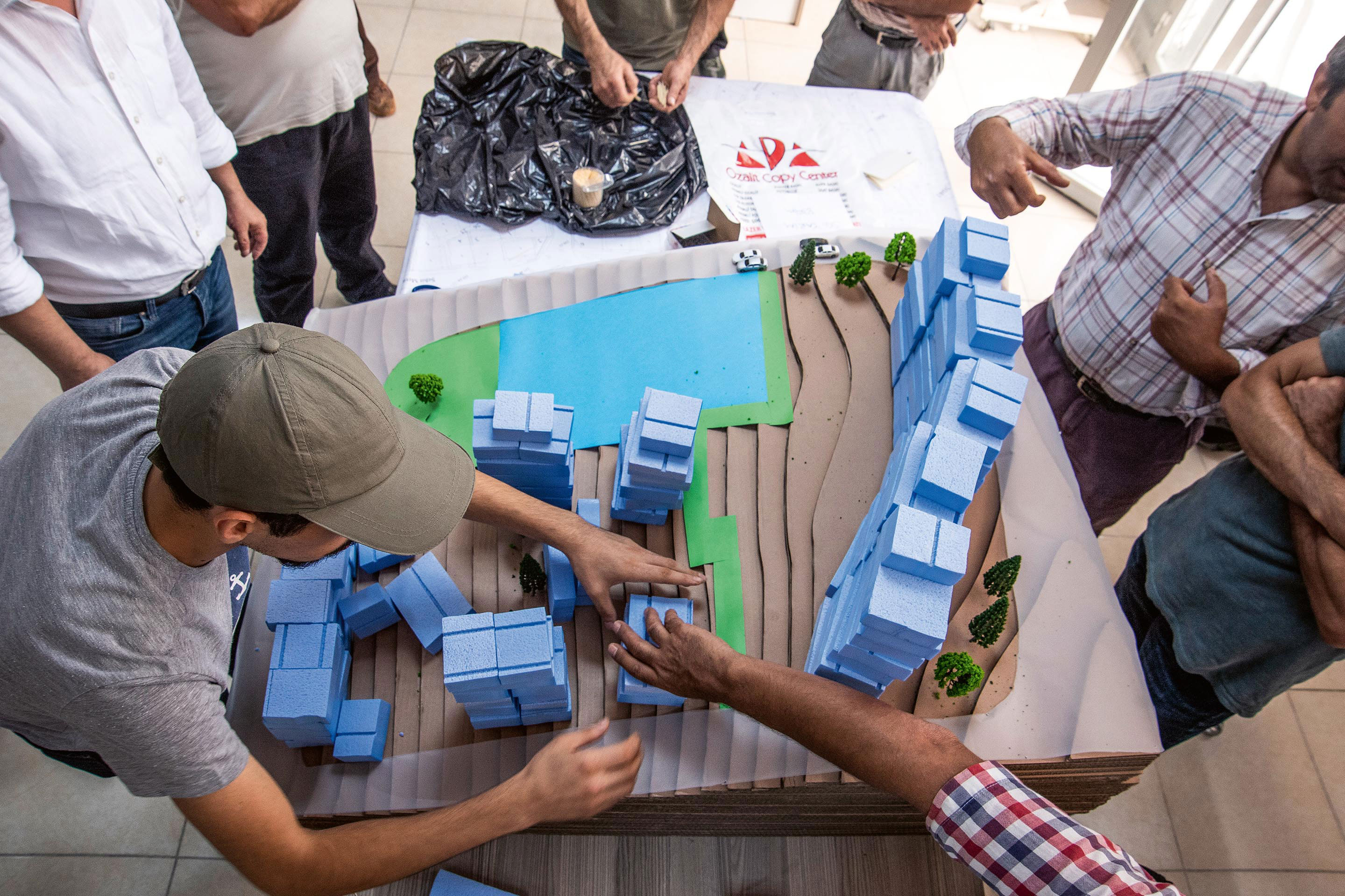 Atelier participatif: les habitants placent les unités d’habitation en bleu sur un îlot pilote où se trouvent déjà un parc (en vert) et un dispensaire de santé (grand rectangle bleu).