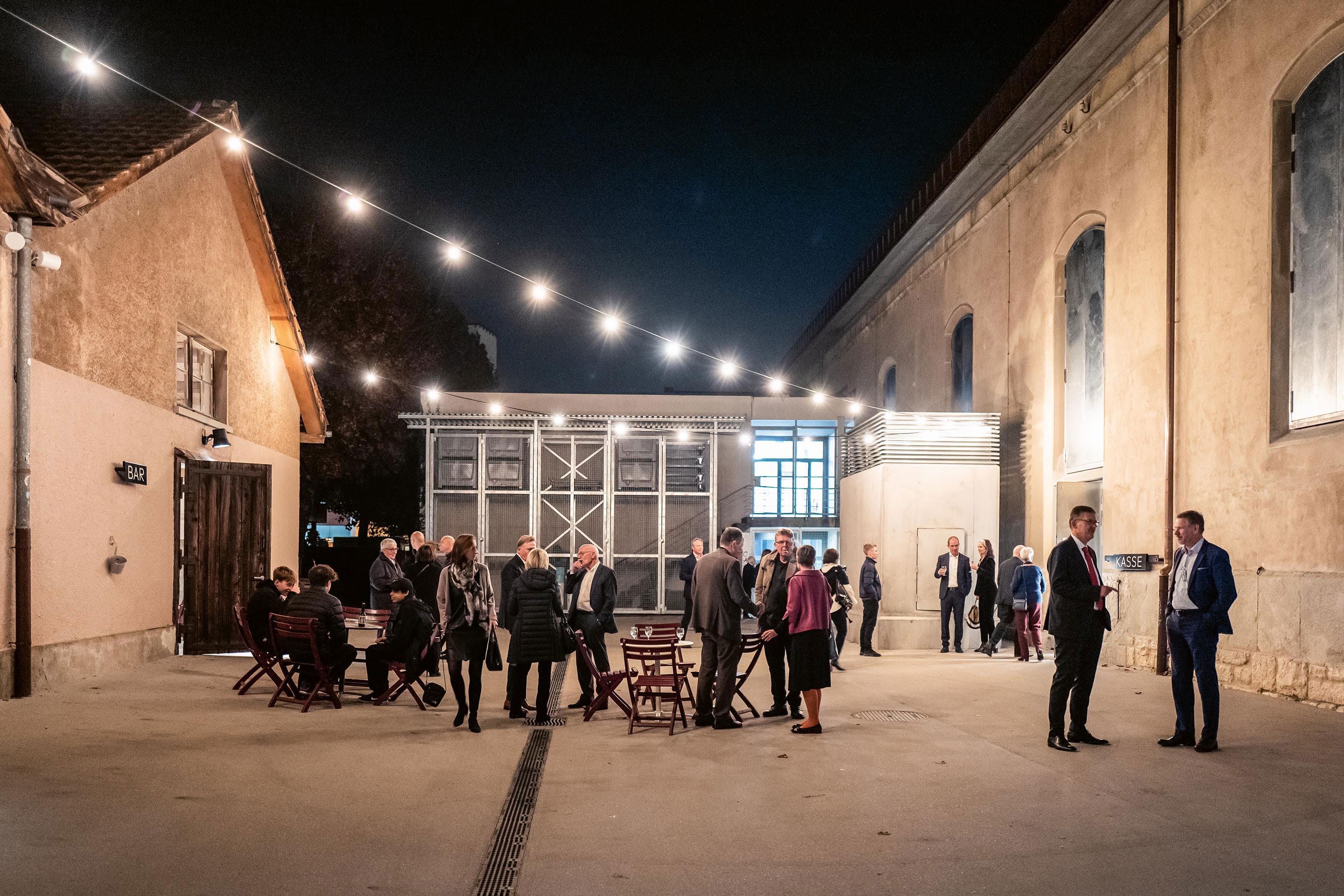 Der hermetische Bau lässt sich schwellenlos zum umgebenden Strassenraum und zum Hof öffnen. Die ehemaligen Stallungen hinter  der Reithalle nehmen Lager und eine Bar auf. In der ursprünglichen Planung waren an ihrer Stelle Neubauten für Produktionswerkstätten vorgesehen.