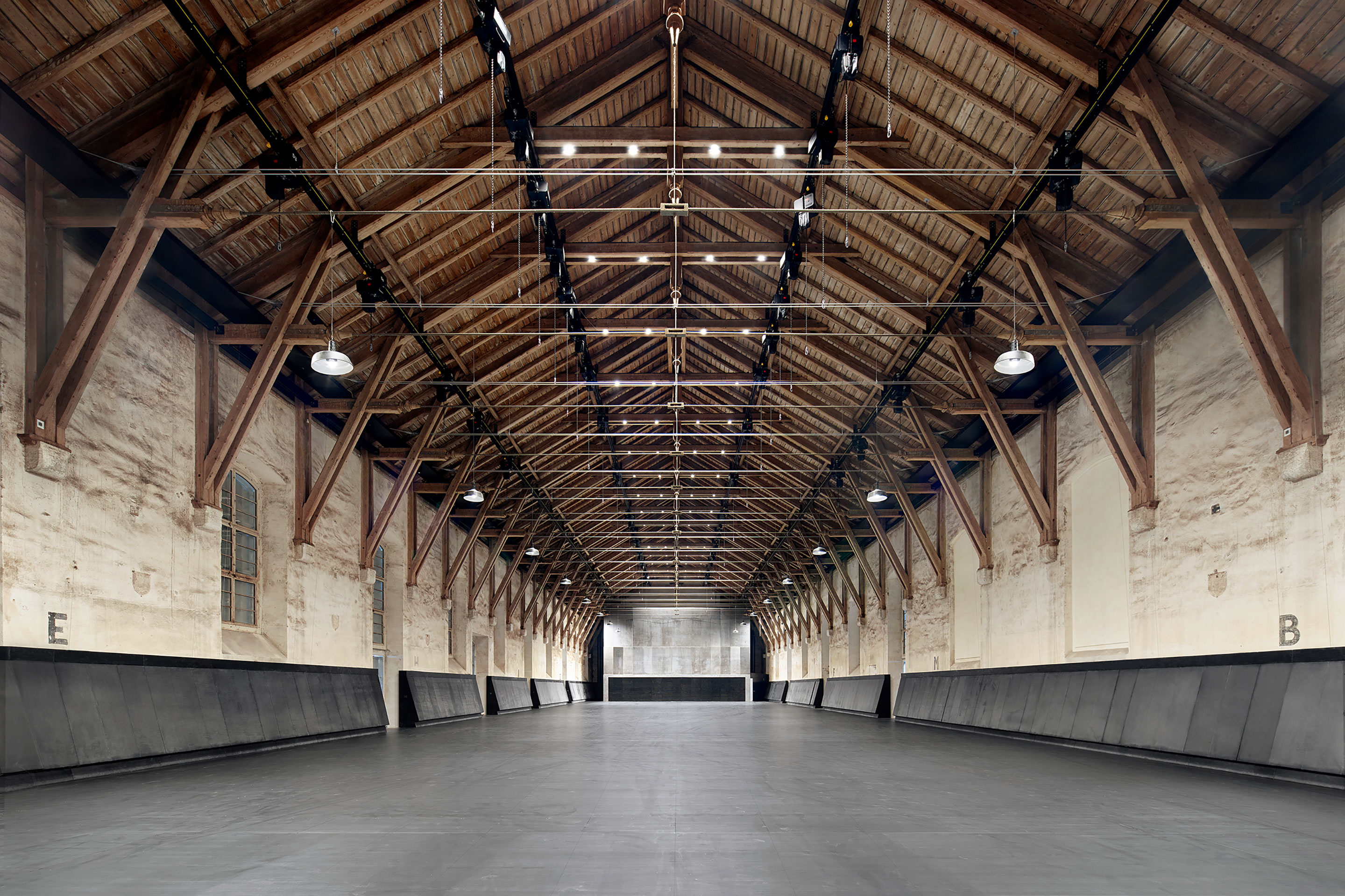 Ohne die eingestellten Bühnen und Zuschauertribünen wirken die drei Komponenten der Raumhülle – Dachstuhl, Natursteinmauerwerk und Holzboden – wie unberührt.