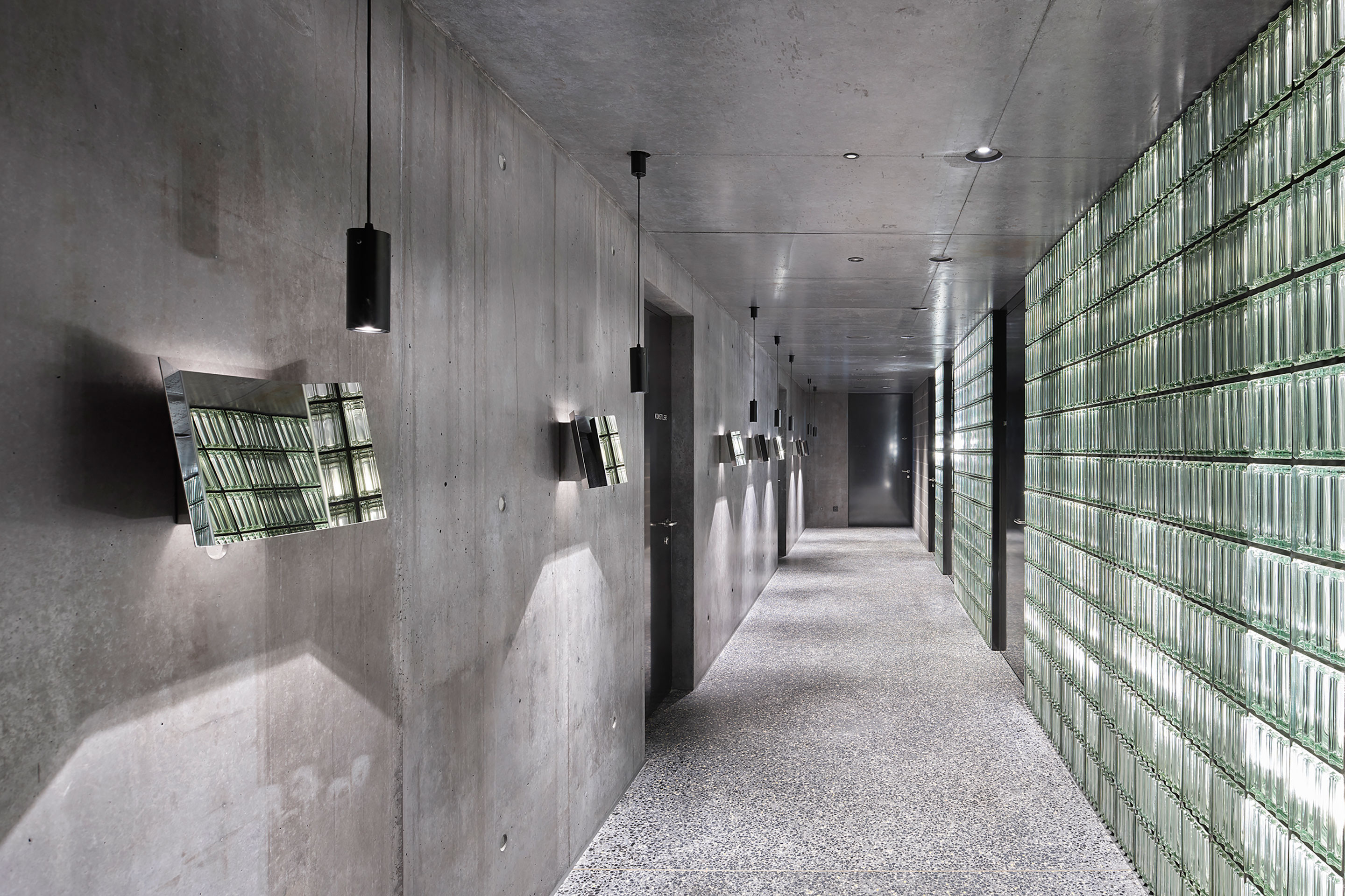 Im Flur vor den WC-Räumen säumen Spiegel wie gefaltete Notenblätter den Weg. Hier können die Darstellenden vor dem Auftritt einen letzten Blick auf sich werfen. Steht der Kubus dem Publikum offen, kann es beiläufig sein Erscheinungsbild überprüfen, ohne dafür die WCs zu belegen.