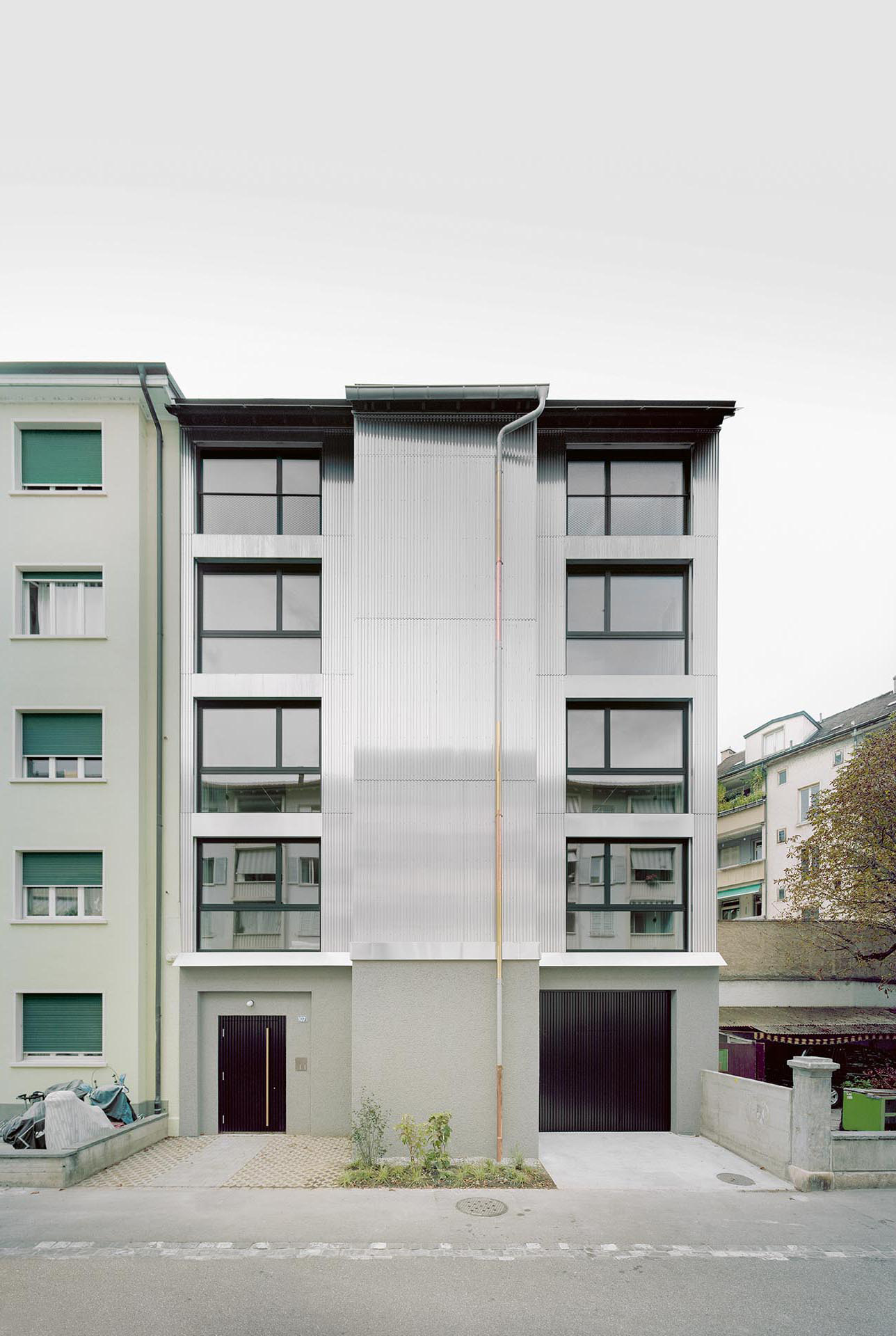 Für die Strassenfassade fertigte die Spenglerei eine Metallkonstruktion, die sie auf den Holzelementbau montierte und mit Trapezelementen aus Roh-Aluminium verkleidete.