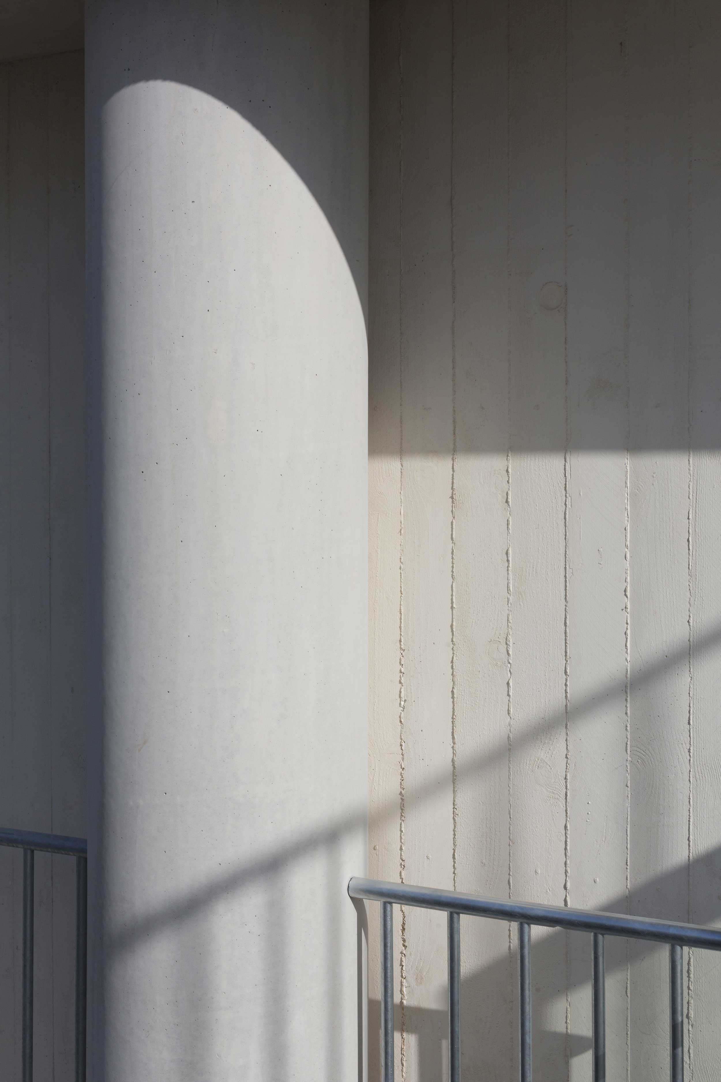 Le bois peint et les marques sur le béton du coffrage en bois interagissent et se confondent.