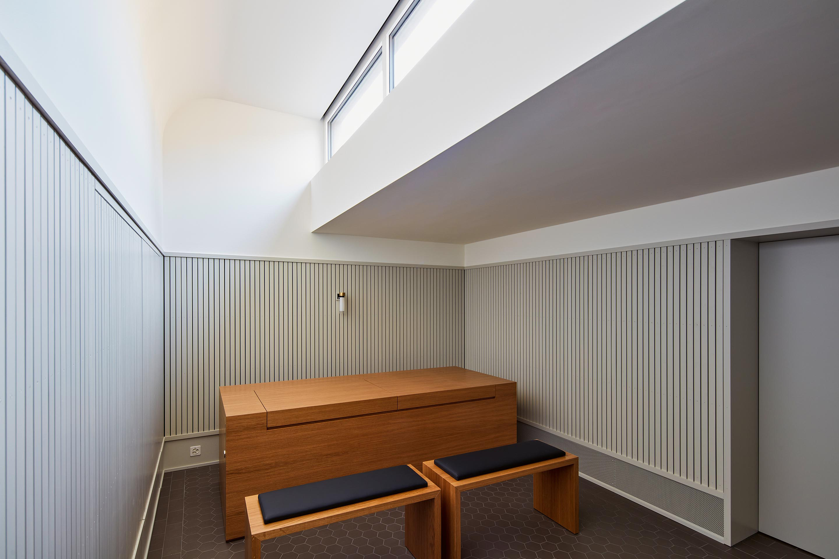 Die Andachtsräume sind intime Orte des Abschieds. Warme Materialien, das Oberlicht und sechseckige Bodenfliesen bestimmen die Raumatmosphäre.