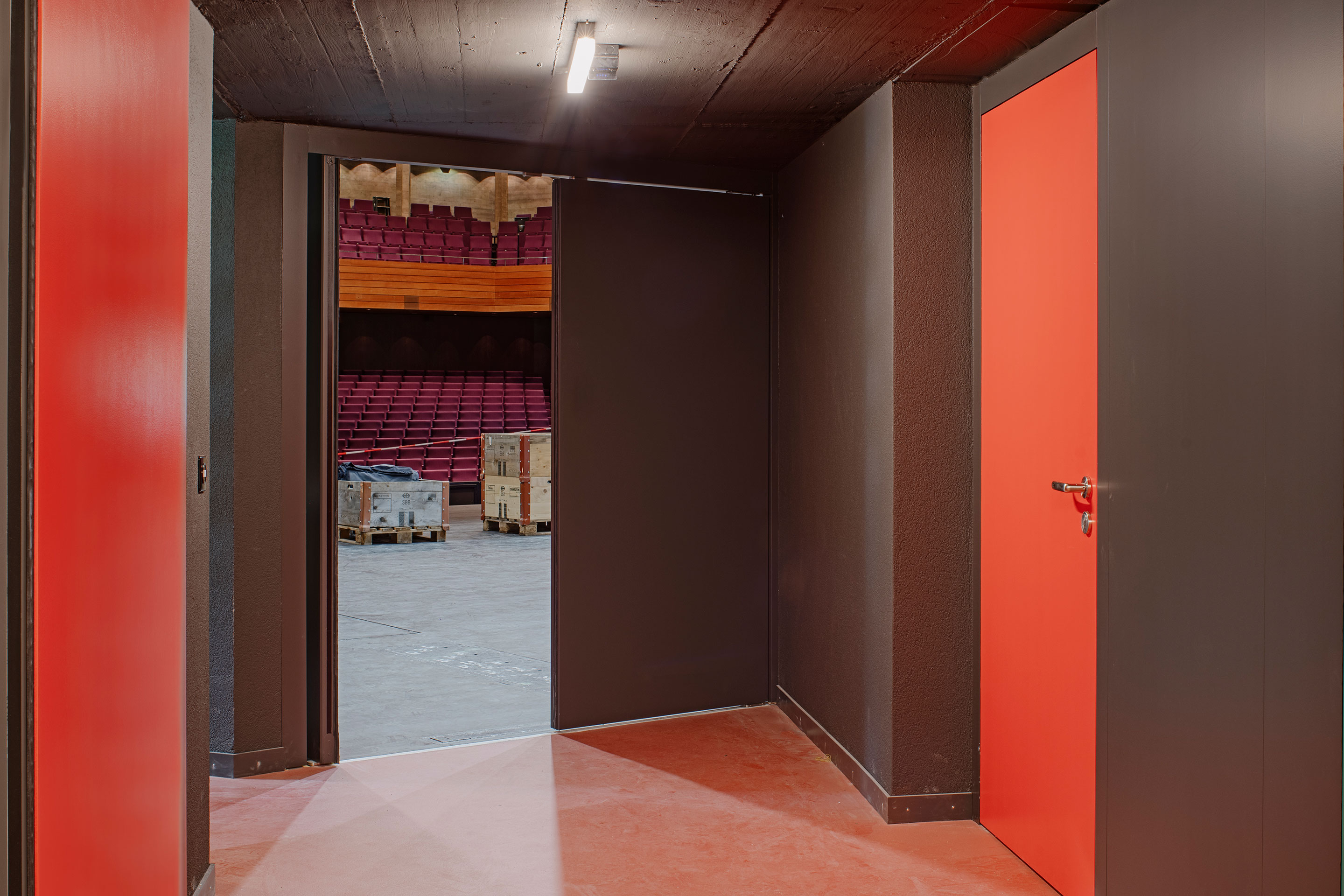 Hinter den Kulissen ist die Materialisierung vor allem funktional. Mit dem Umbau kam ein roter Boden. Rot sind auch jeweils die Türen, die auf die Bühne führen. Alle anderen sind grün – ein einfaches Mittel zur Orientierung.