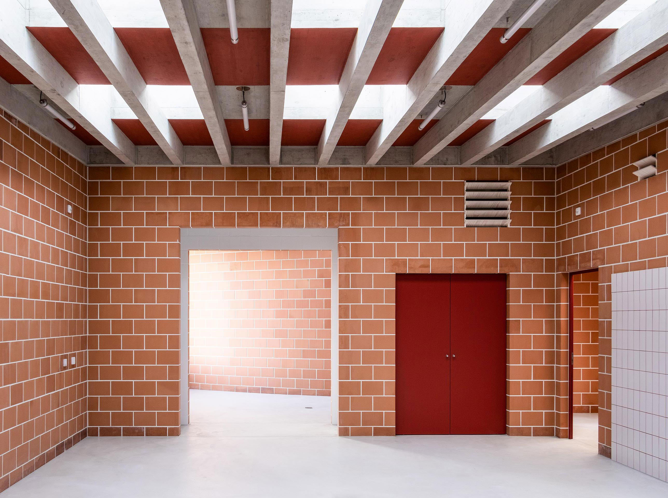 L’intérieur de la Maison des Jardiniers est fait de murs de briques en terre cuite, sur lesquels reposent des poutres en béton qui é voquent une pergola.