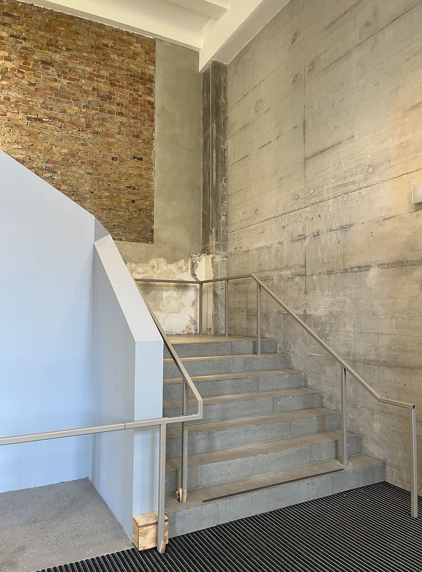 Der Treppenlauf vom EG ins 1. OG lagert sich als neue Schicht in den Bestand der Eingangshalle.