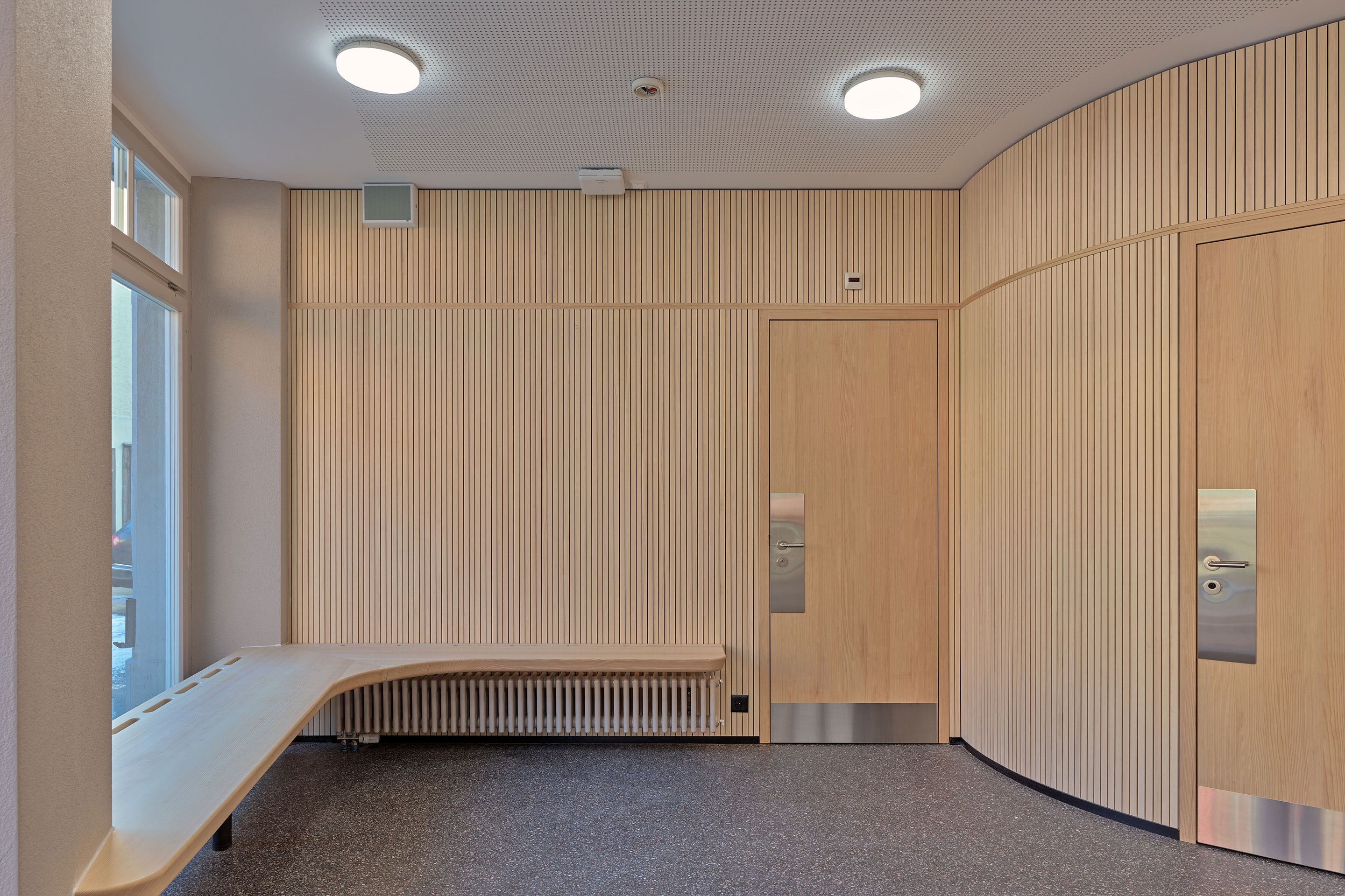 Die Wände des neu gestalteten Empfangs, die mit dünnen Tannenholzleisten verkleidet sind, nehmen den Schwung der Fassade auf.
