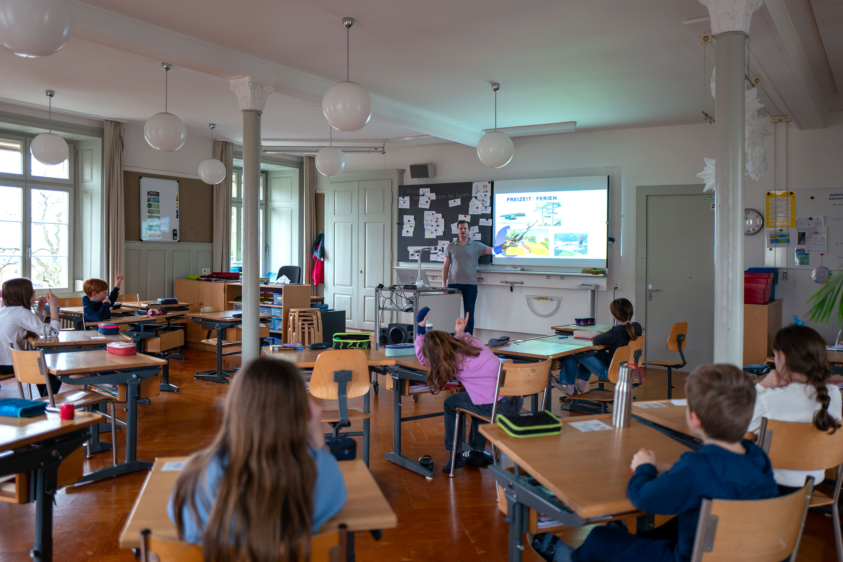 Merki präsentiert verschiedene Alltagsobjekte und deren Bezug zu Ingenieurthemen vor der Klasse.