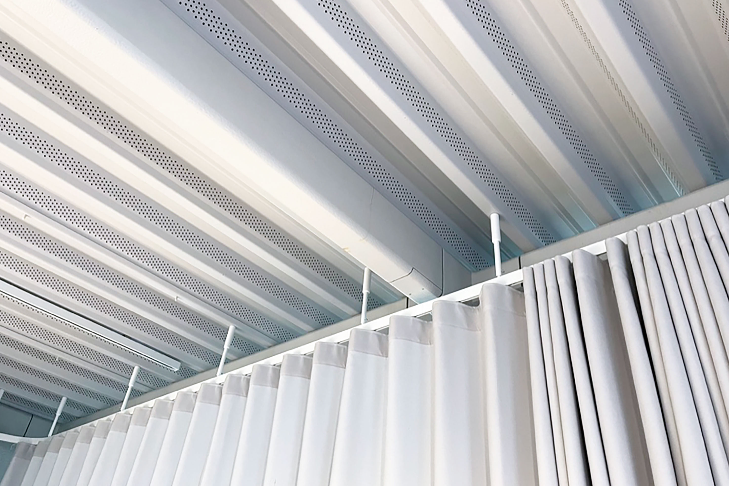 De tout petits trous dans la tôle trapézoïdale mettent en évidence l’isolation acoustique qui se cache derrière