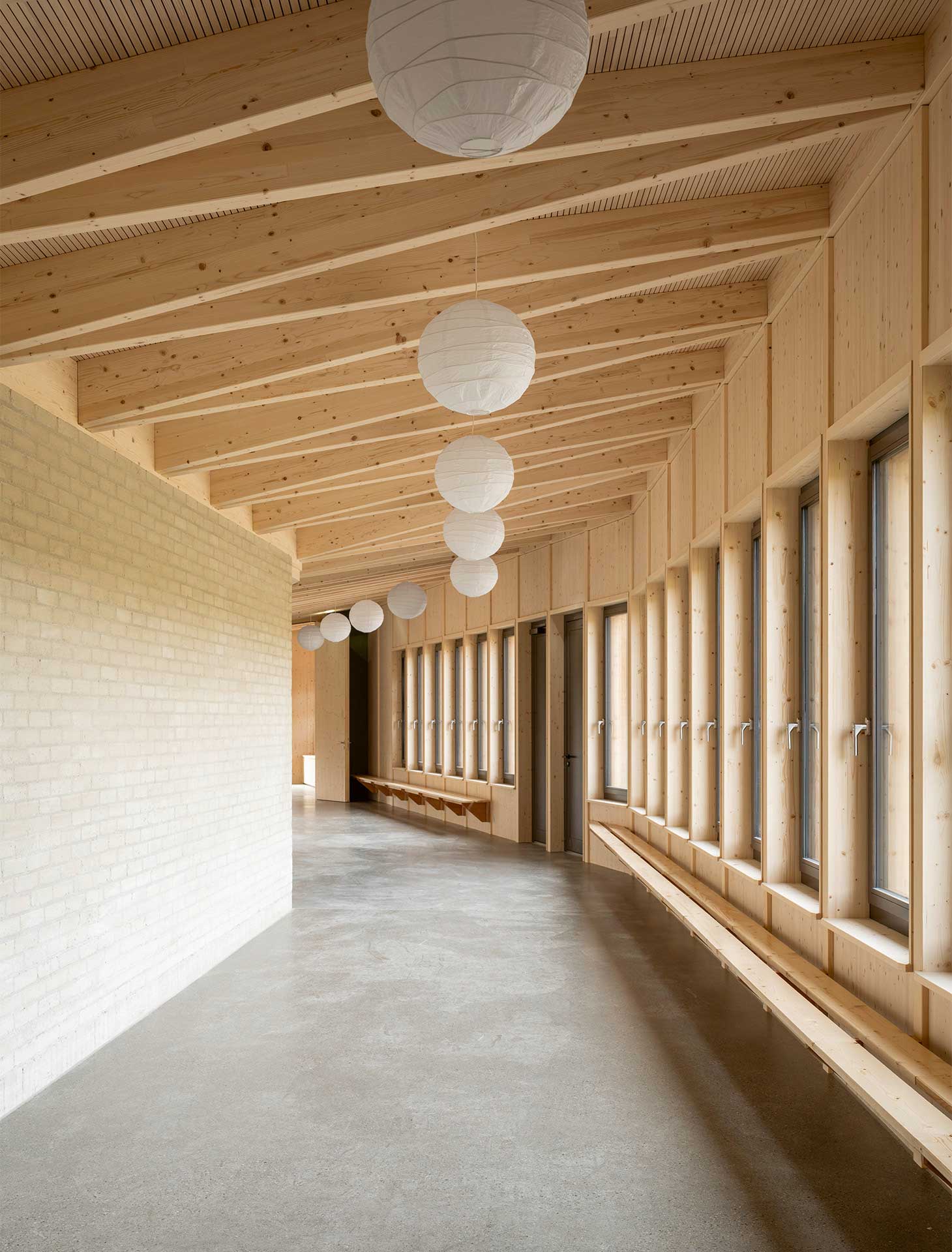 Le mur en brique de terre crue qui longe la large circulation intérieure a permis aux élèves et à des apprentis maçons de se former et de participer à la construction de l’école.