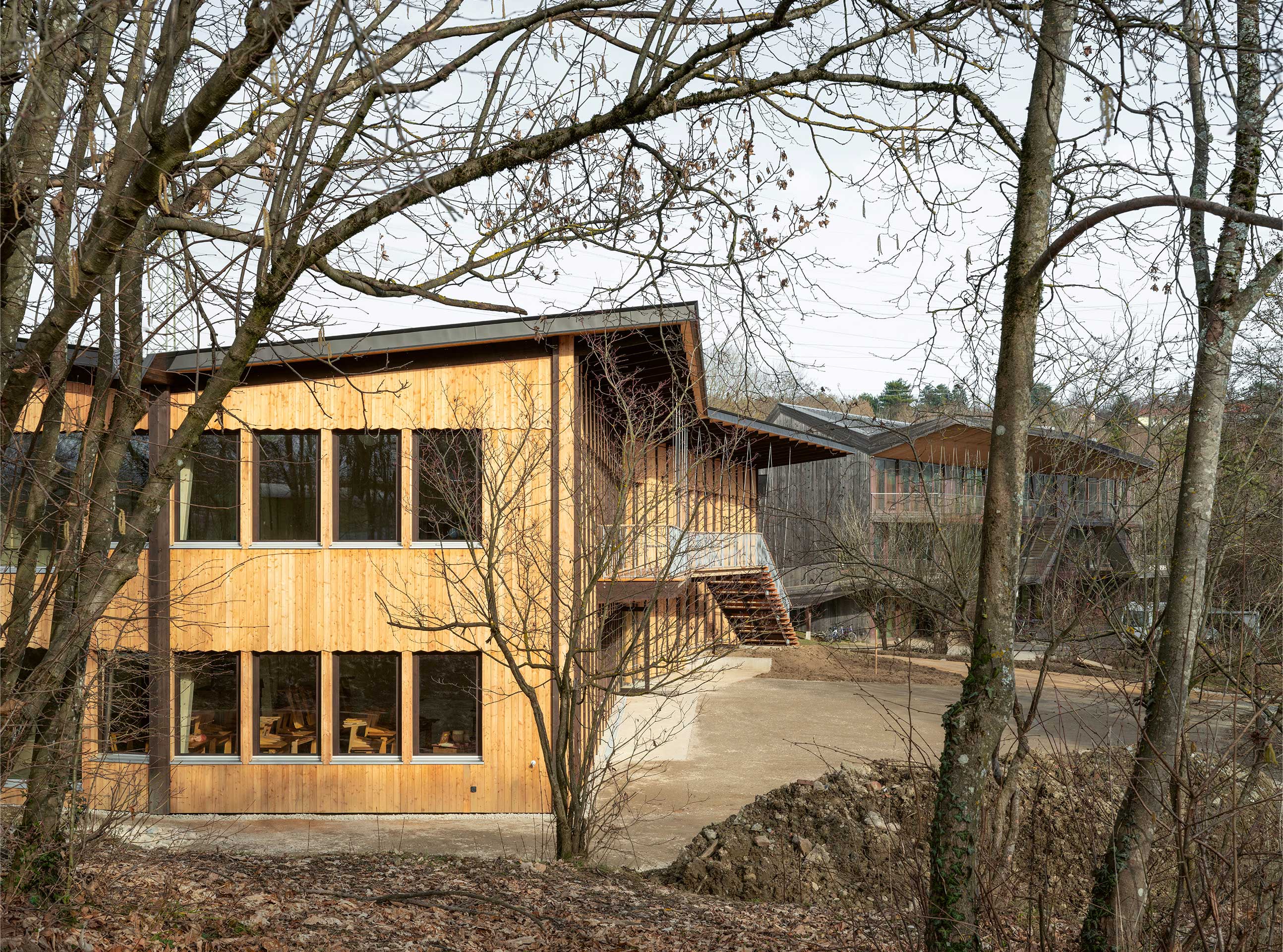 Dans la continuité du pavillon B1, le pavillon B2 reprend le large avant-toit, l’escalier extérieur et la matérialité du bois.