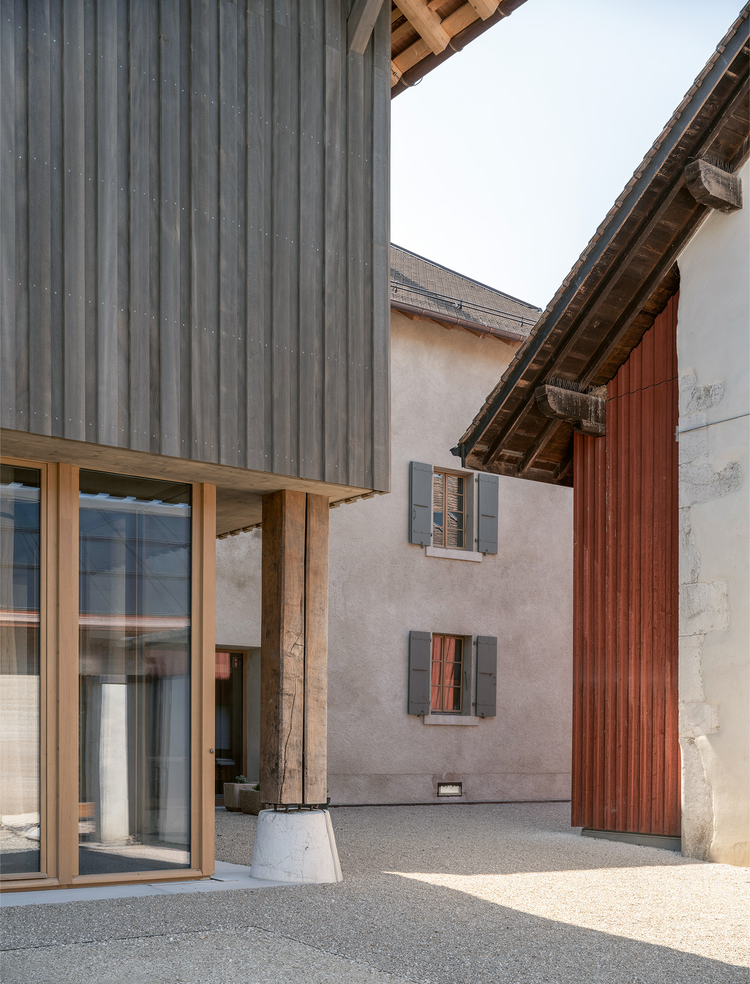 À l’arrière, le bardage en bois, les seuils en pierre et les pièces de charpente rénovées se réfèrent à l’existant.