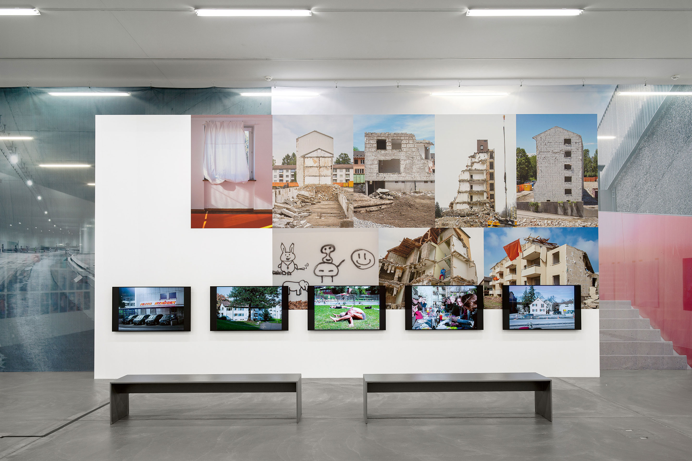 Ausstellungswand mit Abbruchhäusern und Bildschirmen.