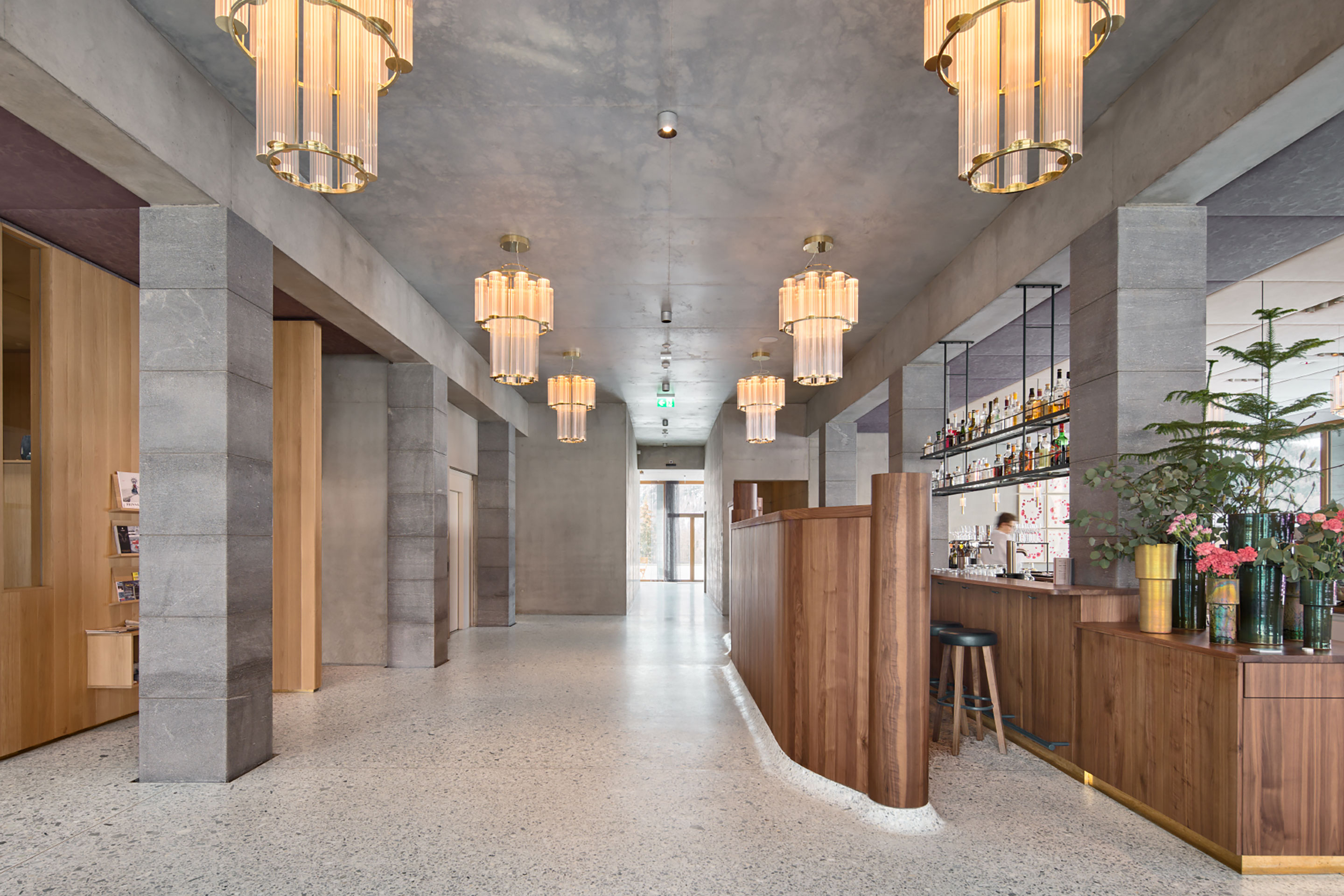 Ein langer Bartresen bildet die innere Flanke der Restaurants. Sorgfältig gearbeitete Bauteile wie der Terrazzo aus Bernina-Gestein mit eingelegter Jade oder die geschwungene Rückwand aus Schwarznussholz zeigen die Klasse der regionalen Handwerksfirmen.