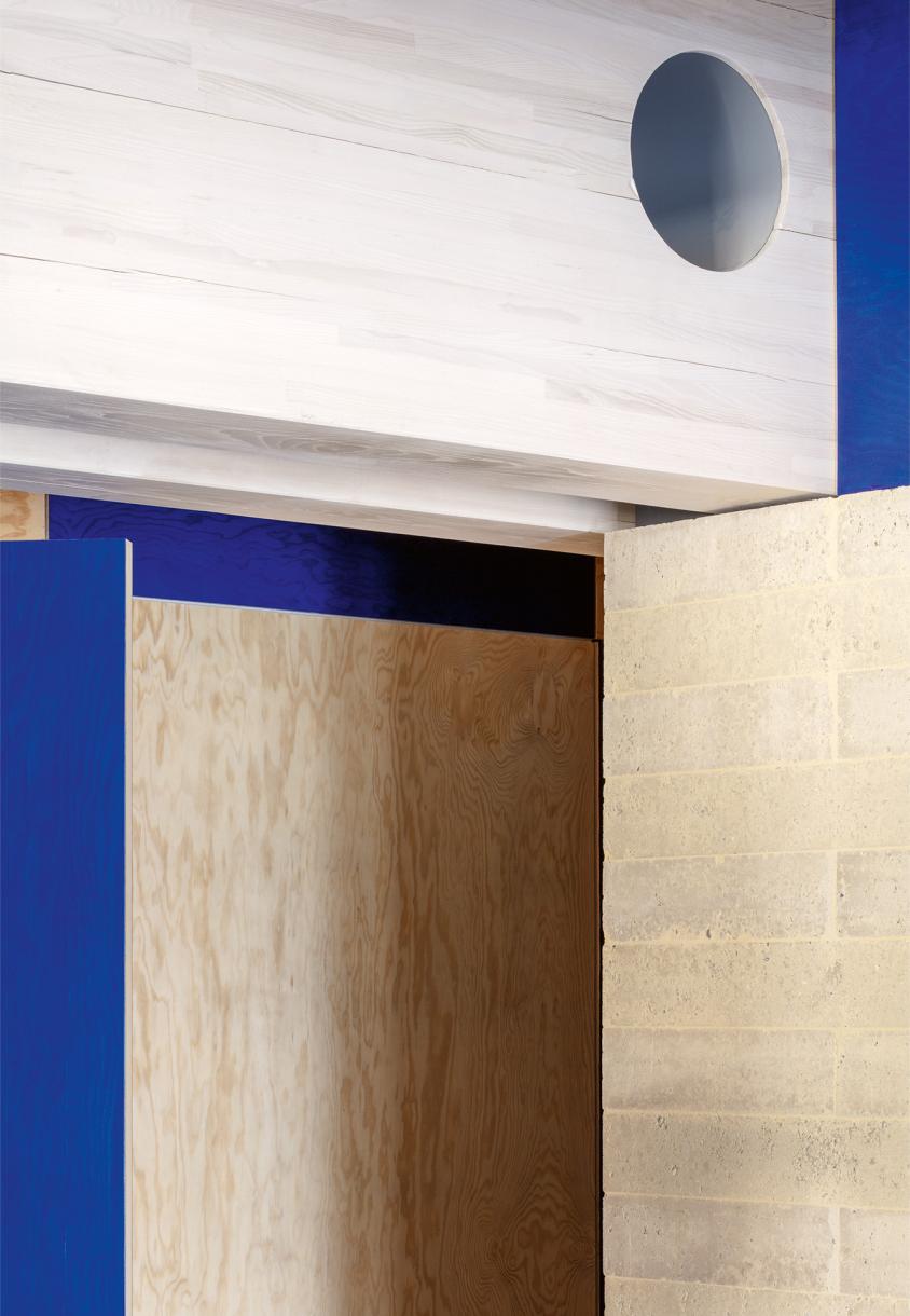 Collision of materials and colours: partition walls made of stabilized Terrapad compressed earth blocks, paired glulam beams, and timber panels.