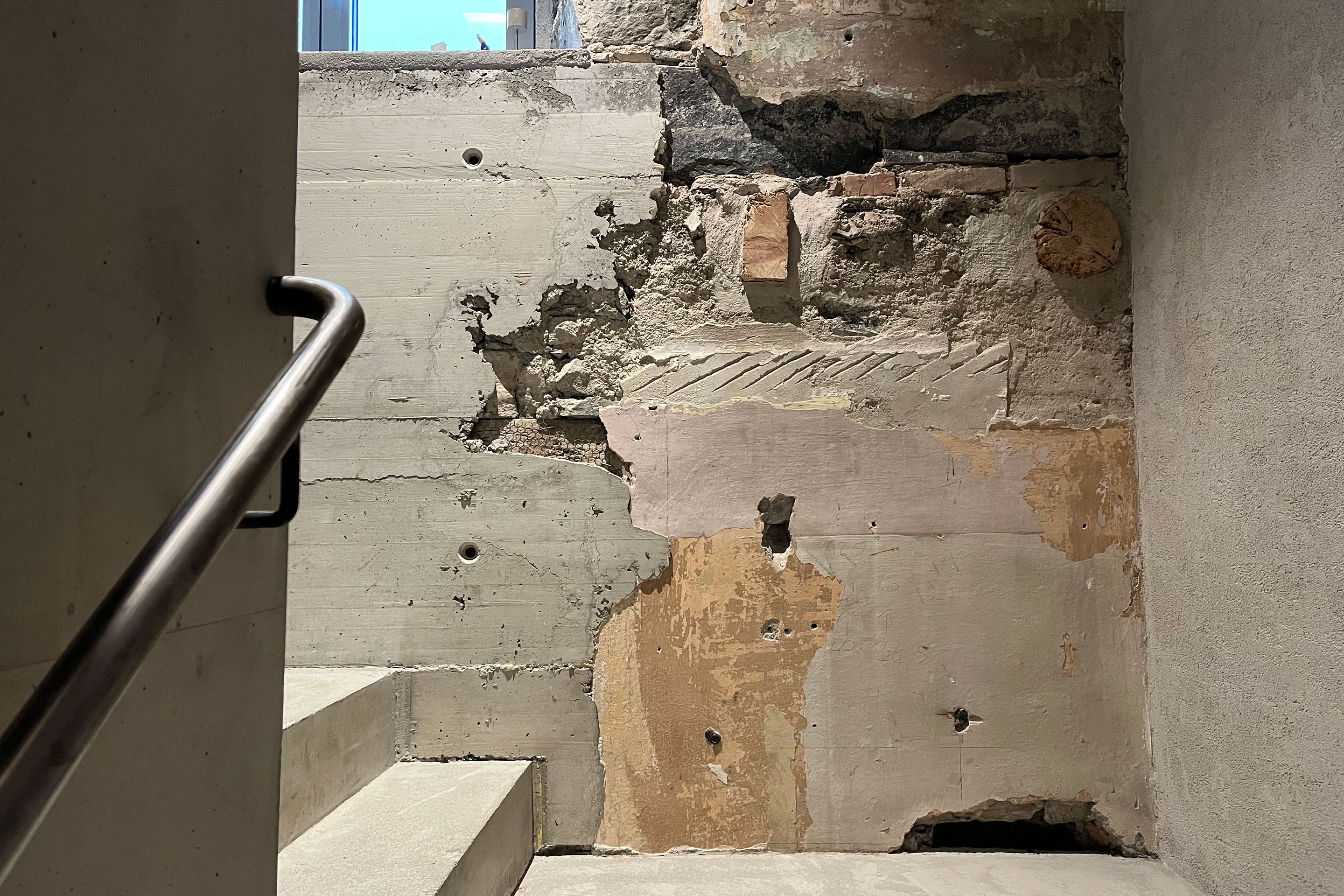 Les incisions dans la substance sont mises en évidence dans la cage d'escalier et témoignent du respect apporté à l'existant. Les différentes pierres, dans des nuances allant du gris au rose saumon, sont encadrées par le béton apparent.