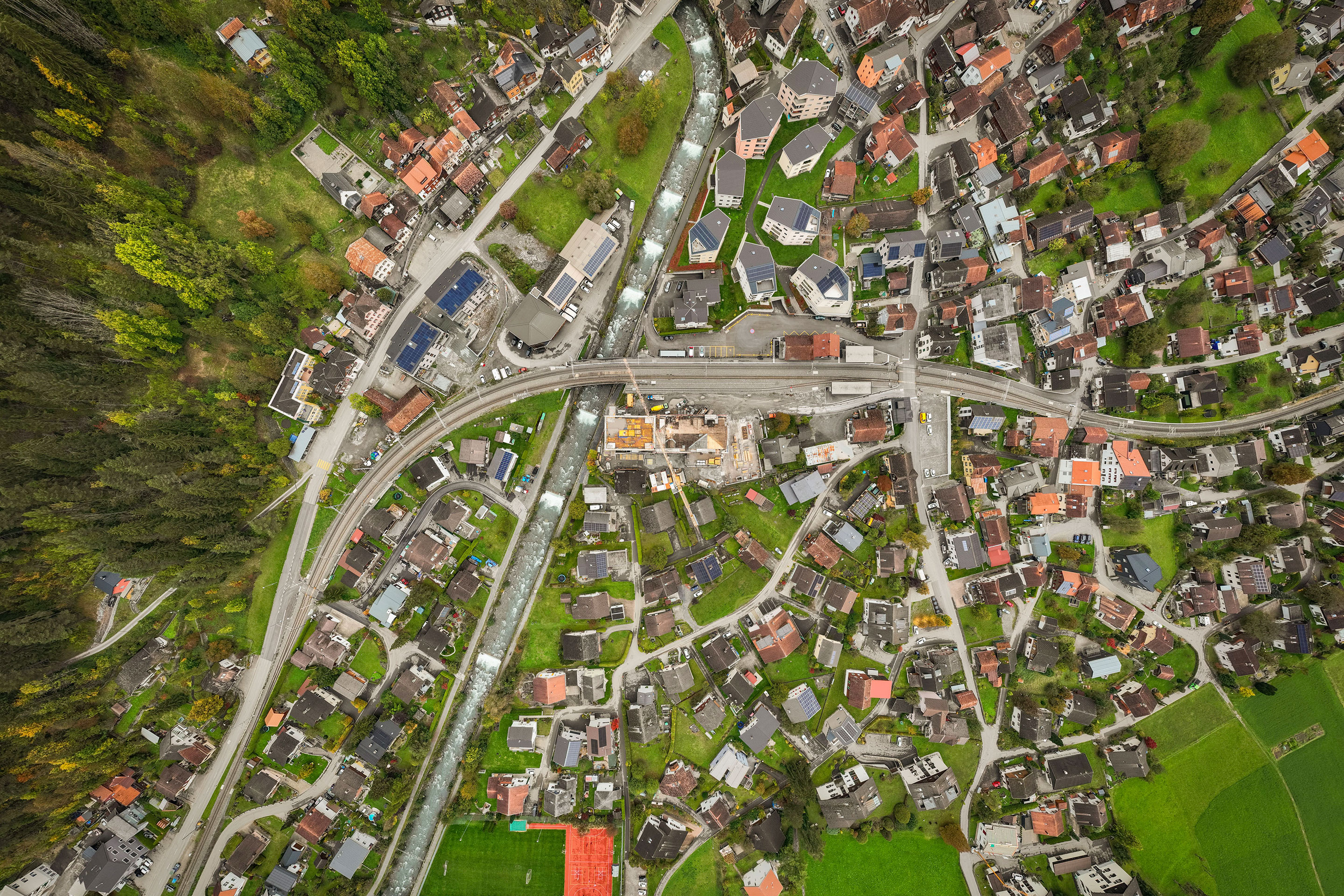 Mühlenturm und Mühlengebäude liegen an der Kreuzung von Bahnlinie und dem Taschinasbach (Bildmitte).