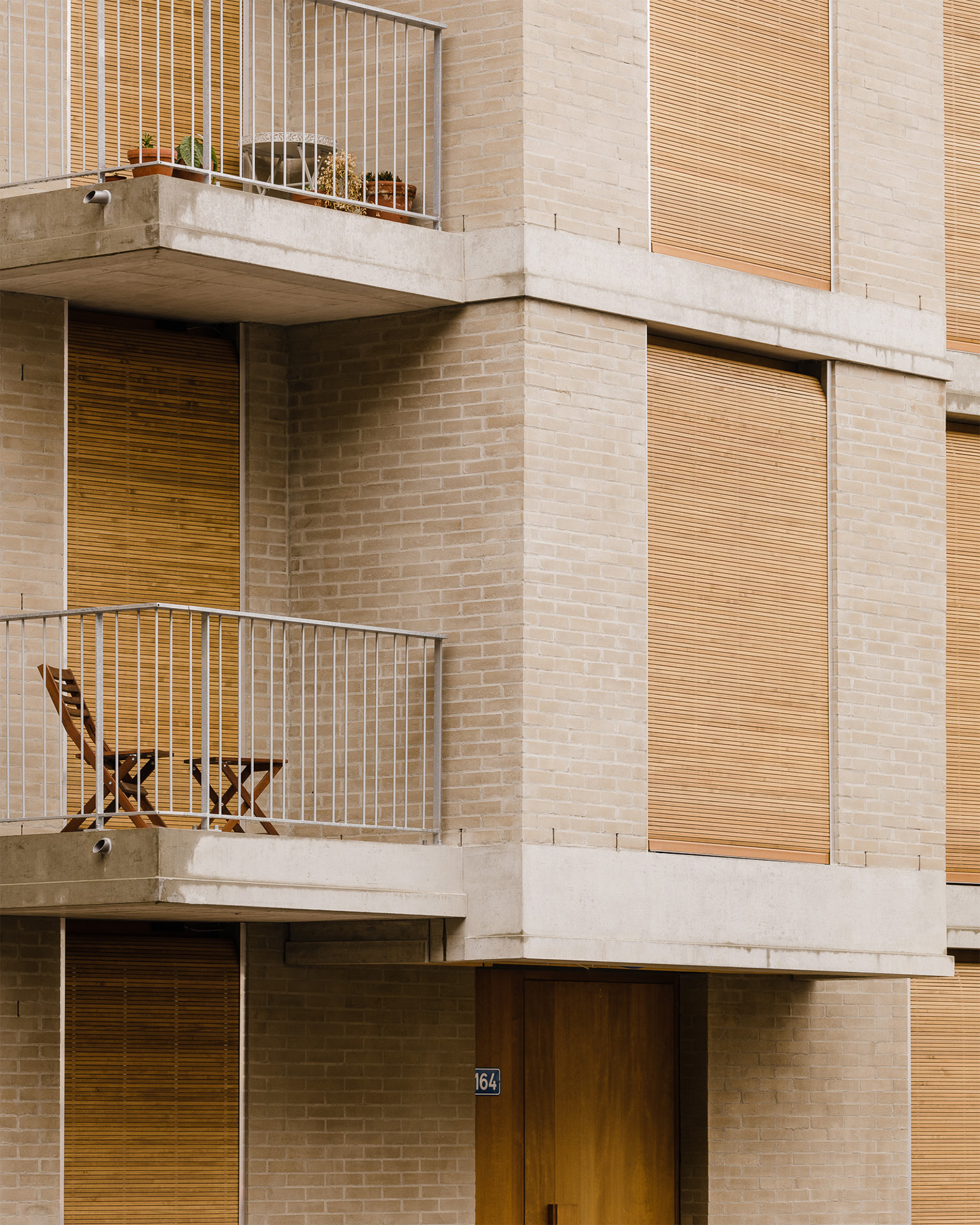Ein schräger Erker ragt aus der Fassade hervor, farblich harmoniert das Zusammenspiel von Lehmziegel, Holz und Beton.
