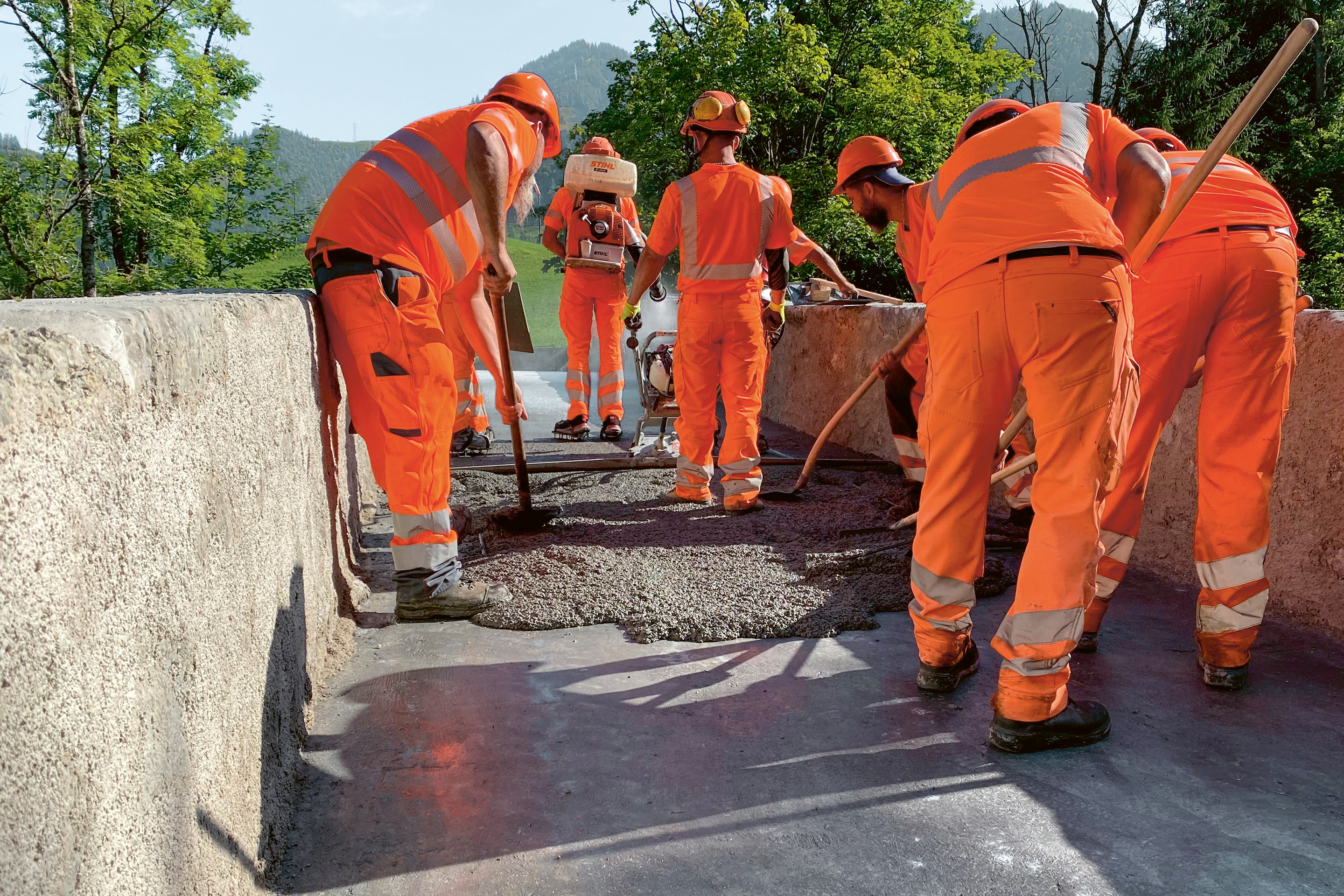 Mise en place du mélange de matrice CFUP avec gravillons sur la couche de fond en CFUP préparée. Le mélange est tiré avec une règle vibrante, avec application immédiate d’un produit de cure.