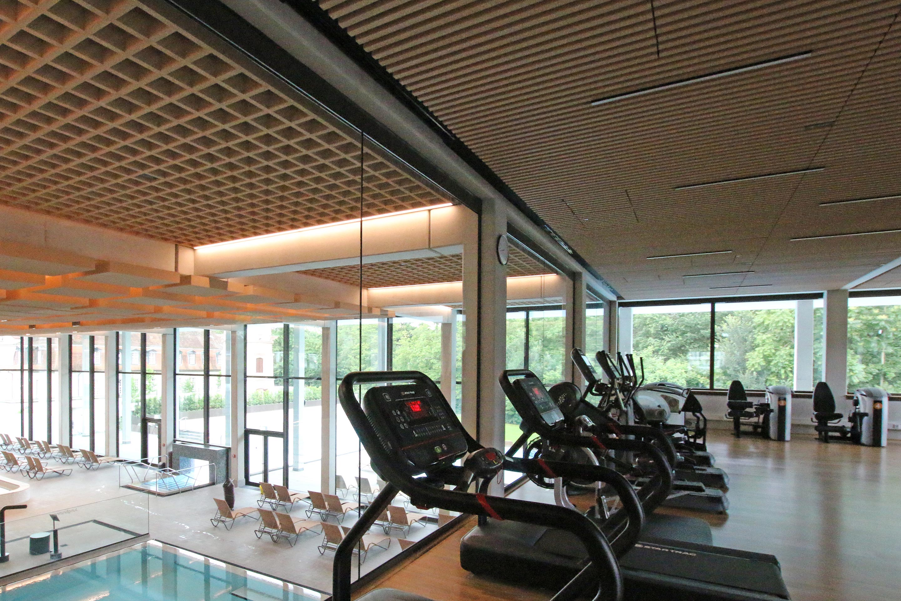 Im Fitnessbereich nimmt man die Lichtstimmungen aus dem Badebereich wahr. Nach aussen reicht der Blick in den nahen Kurpark bis zum Kurhaus.