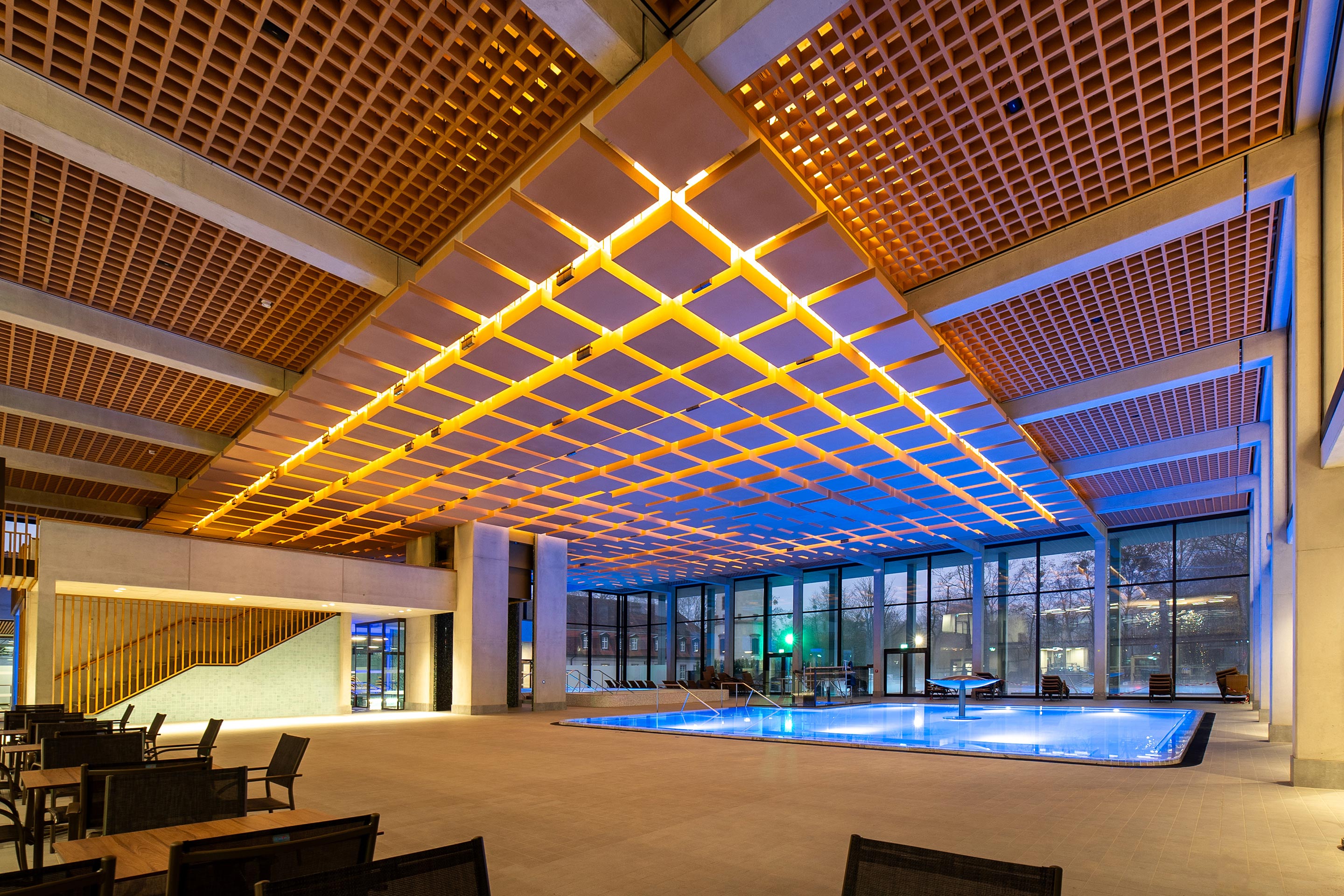 Quadratische Holzkörper in verschiedenen Stärken hängen frei unter der Decke und optimieren die Akustik. Die Form ist eine Reminiszenz an die historischen, auf einem Säulengang gelagerten Quadratdecken des Badehauses 2.