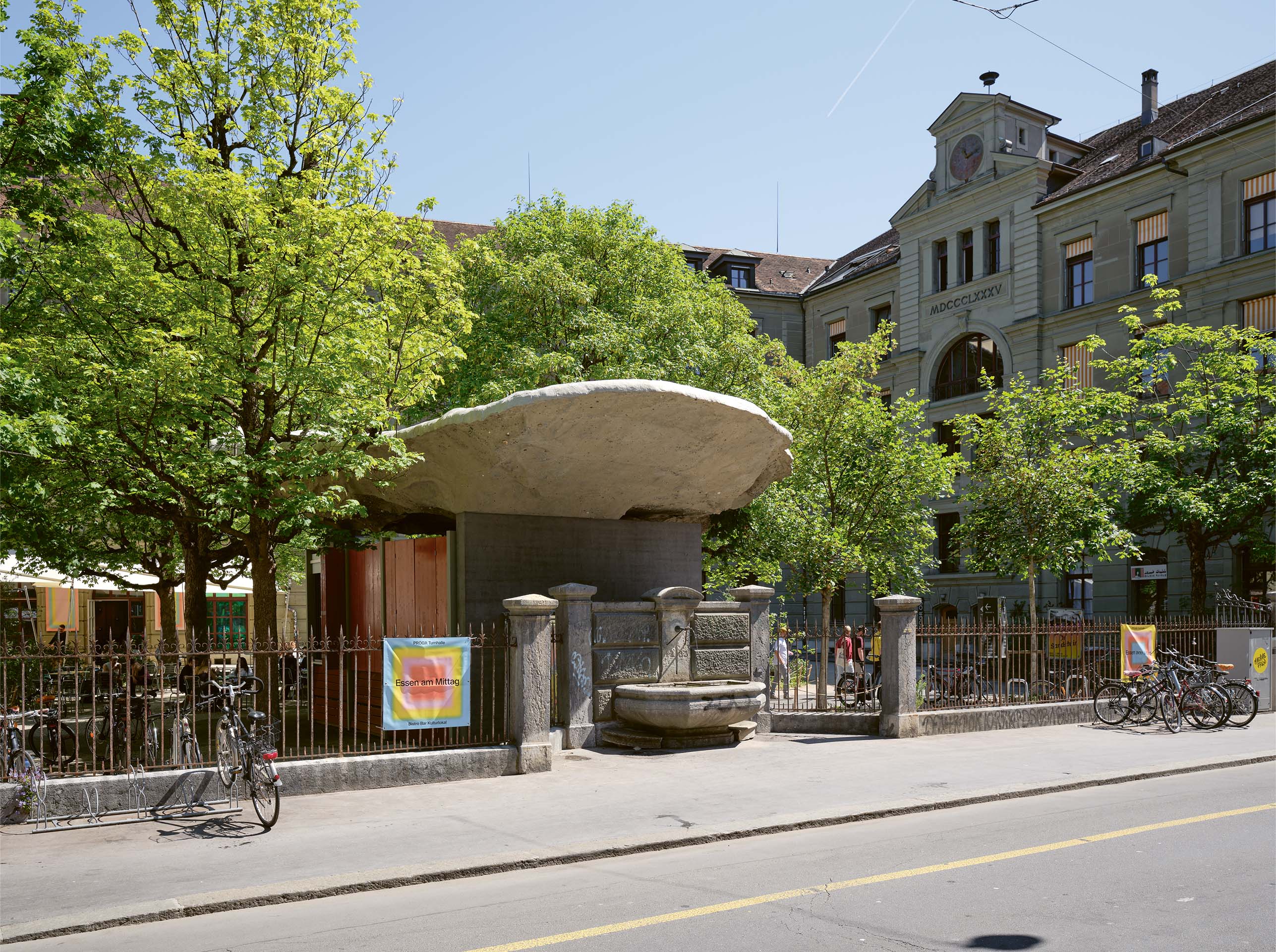 Zur Strassenseite hin kragt die Skulptur weit über den Pavillon hinaus und überdacht den Brunnen im Strassenraum.