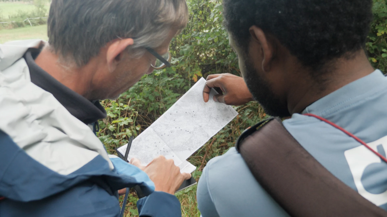 Deux participants consultent une carte papier en pleine nature lors d'une promenade LAC 23.26