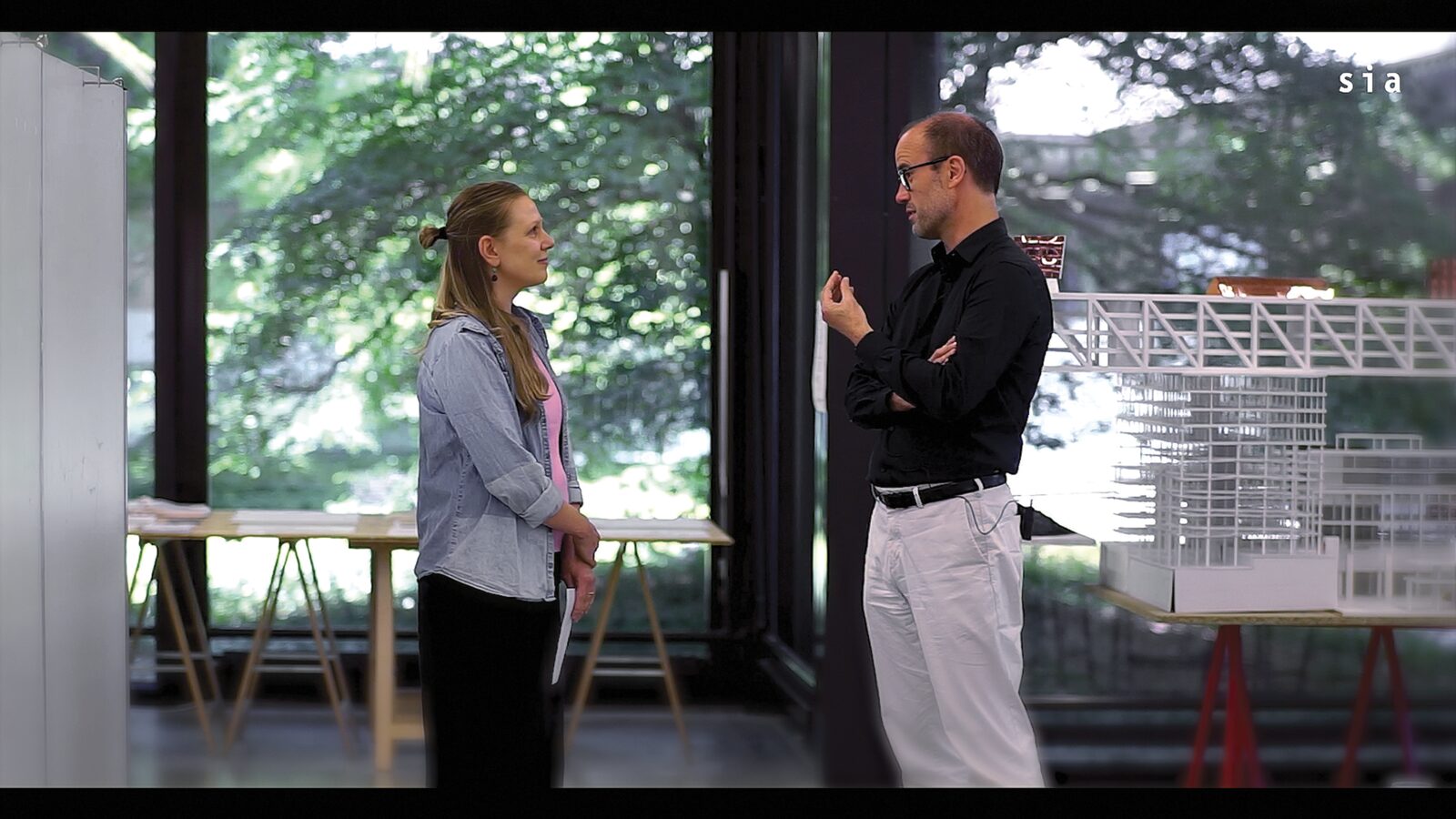 Tom Avermaete et Maria-Theresa Lampe en conversation devant des maquettes d’architecture, image extraite de la vidéo du Prix Master Architecture SIA.