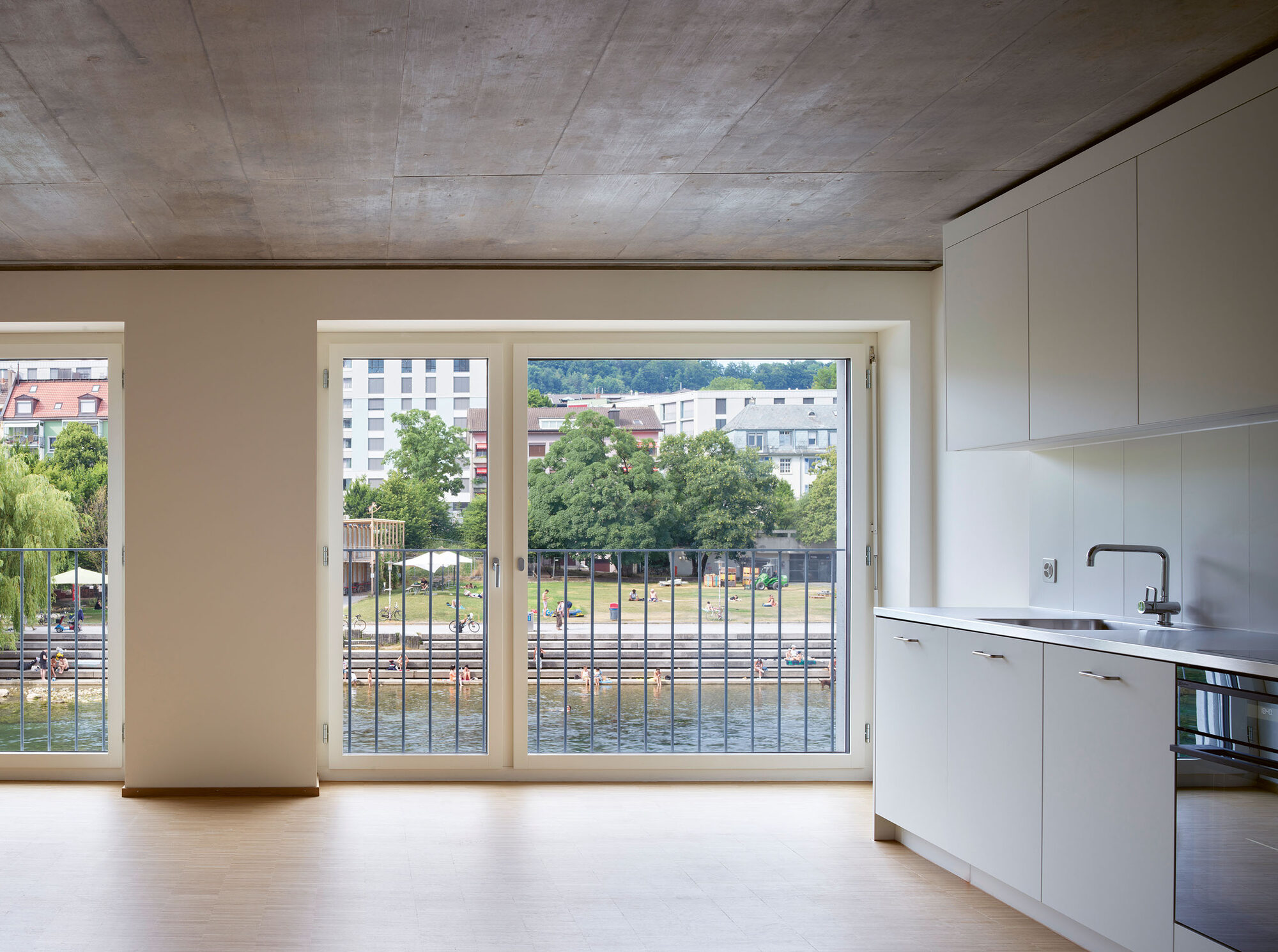Vue depuis un appartement de Depot Hard sur la Limmat et sa promenade, cuisine ouverte au premier plan.