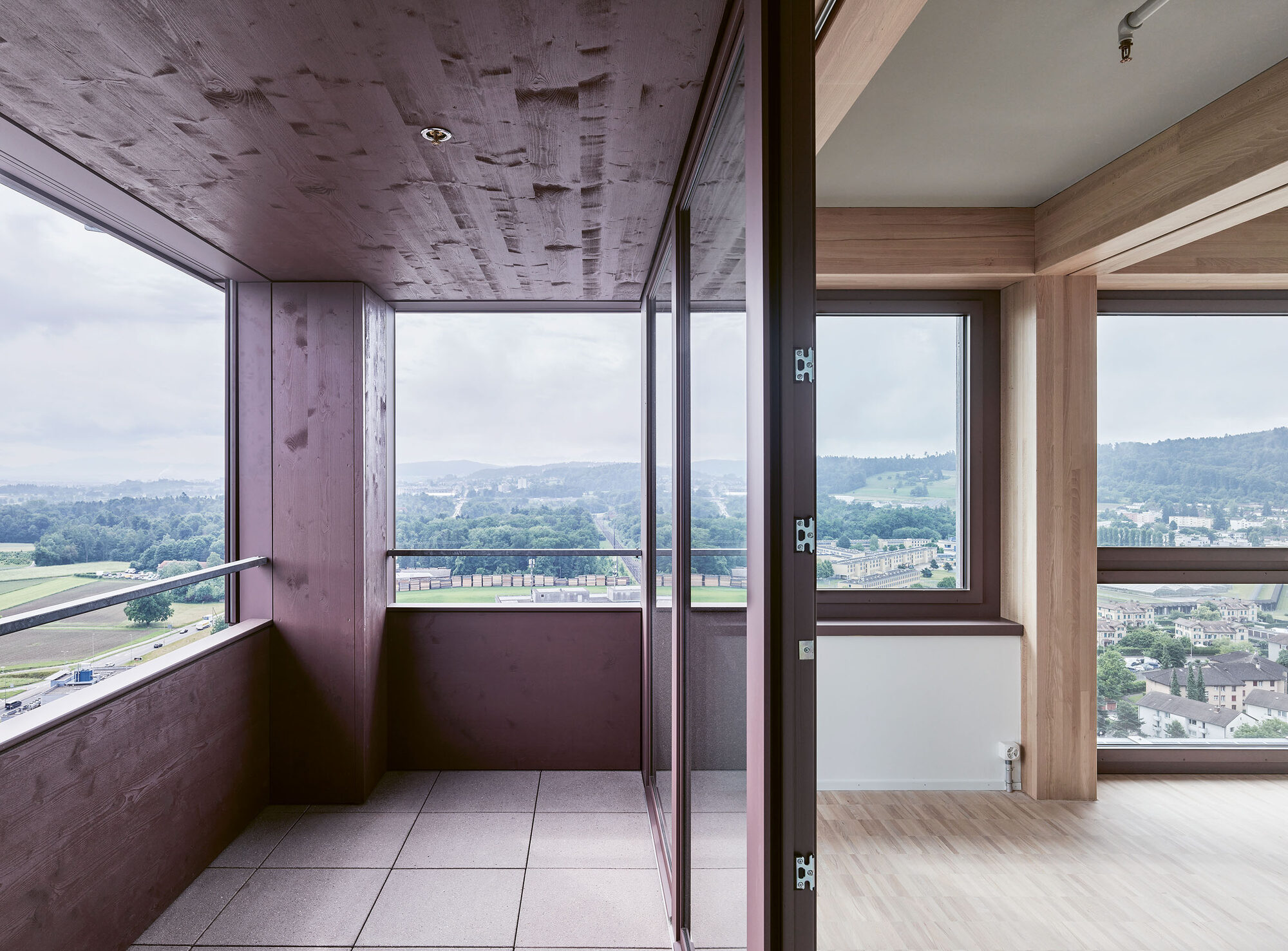 Balcon à la façade rouge et intérieur en bois clair d’un appartement de la tour H1.