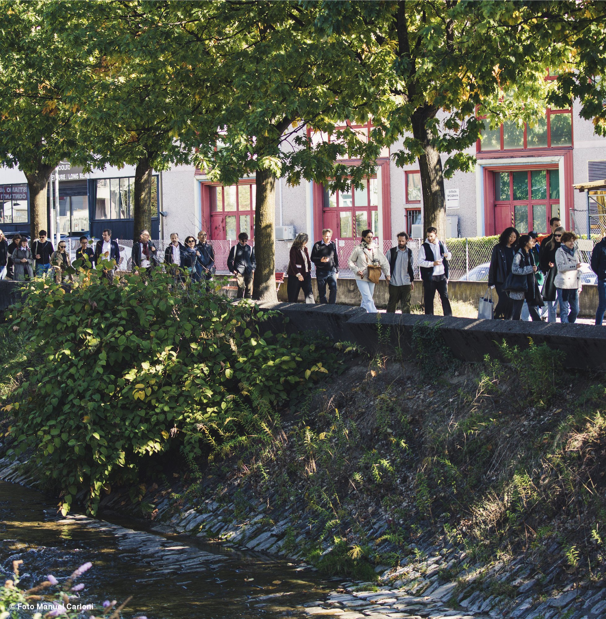 Groupe de participants marchant le long d’un cours d’eau bordé d’arbres, à Bellinzone