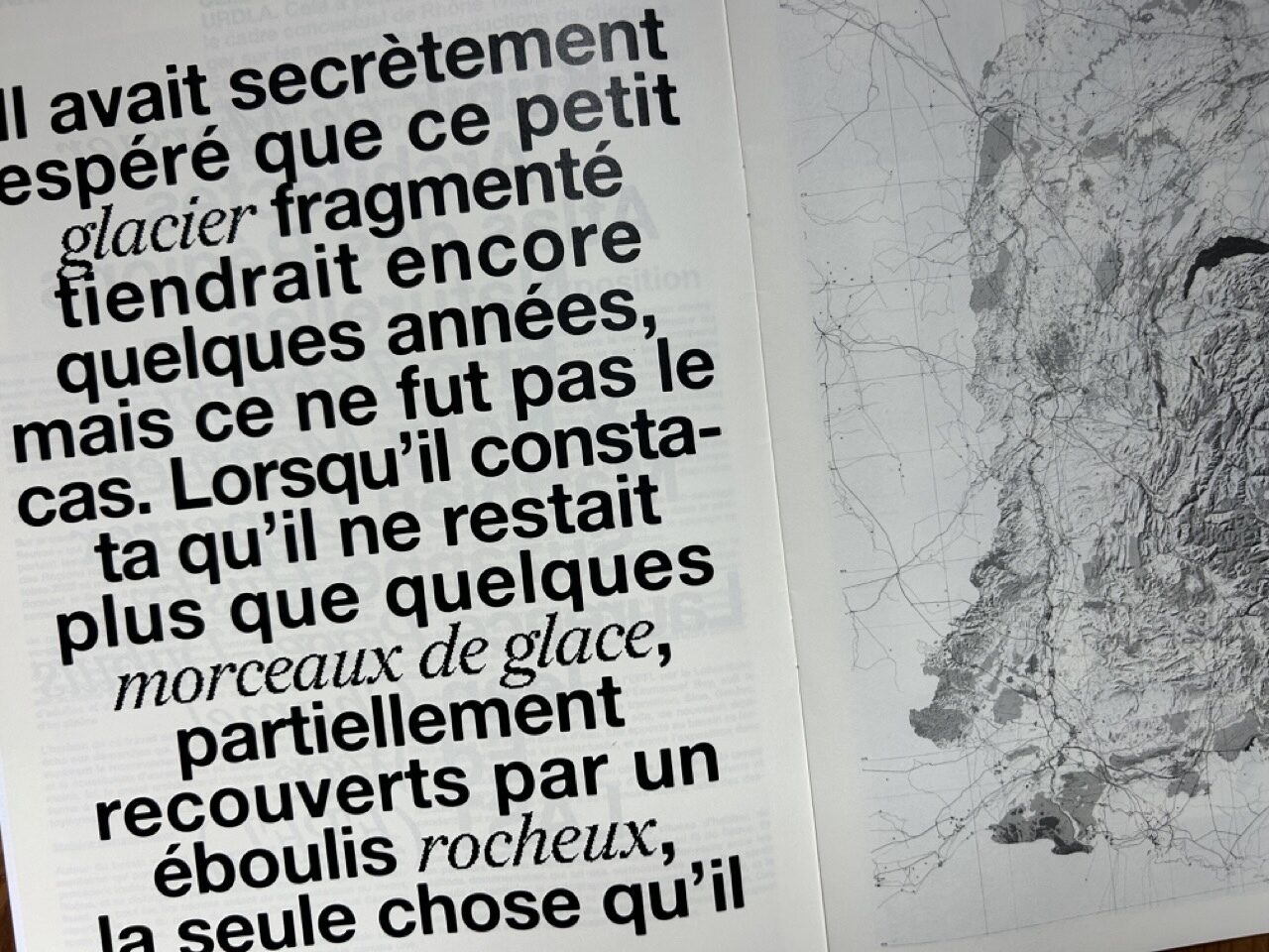 Texte en grands caractères noirs sur un glacier fragmenté, à côté d’une carte en relief.