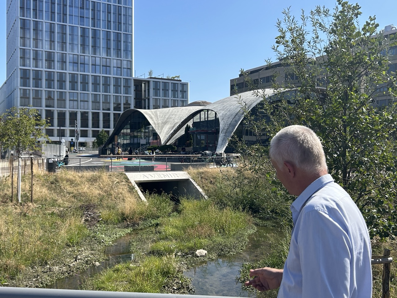 Marco Rampini devant la Drize, avec la voûte en béton du Pavillon Sicli et une tour en arrière-plan.