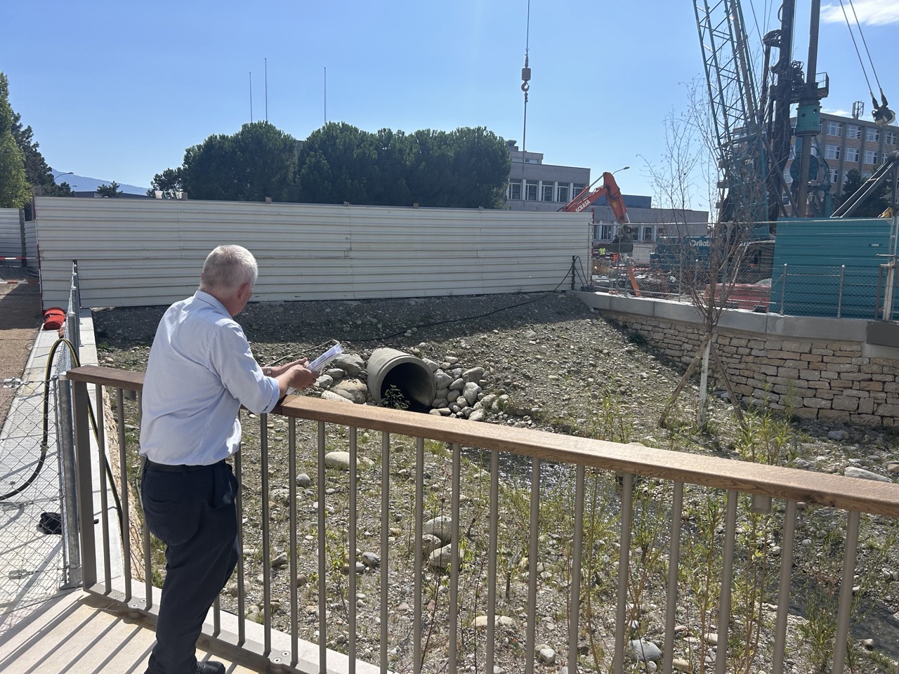 Marco Rampini, appuyé à une balustrade, observe un tronçon remis à ciel ouvert, avec un chantier en arrière-plan.