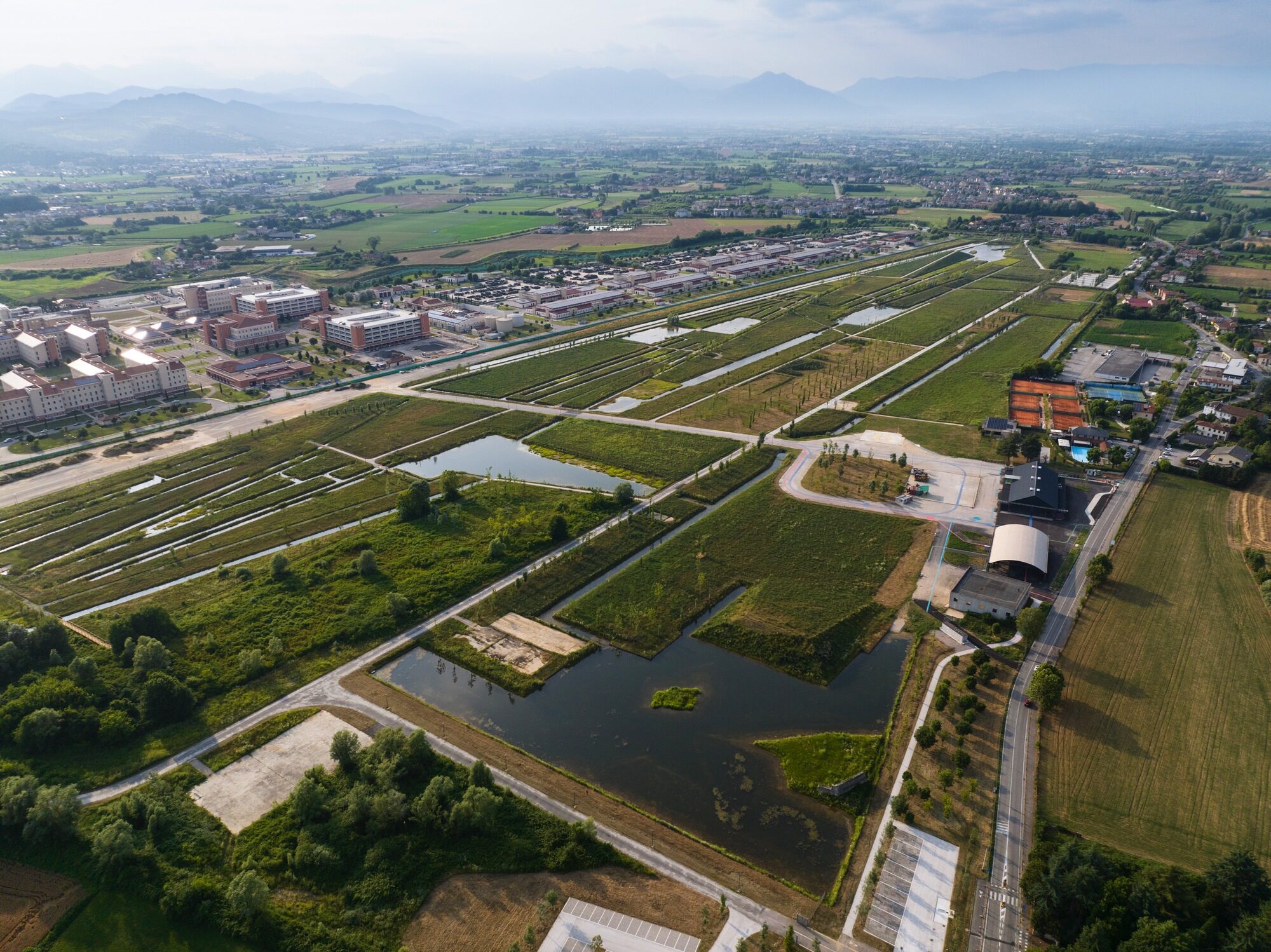 Vue aérienne de l’ancien aéroport de Vicence converti en paysage de bassins et de prairies.